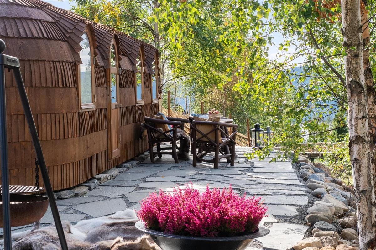 Outdoor area with stone‑slab walkway, table, and lush green trees.