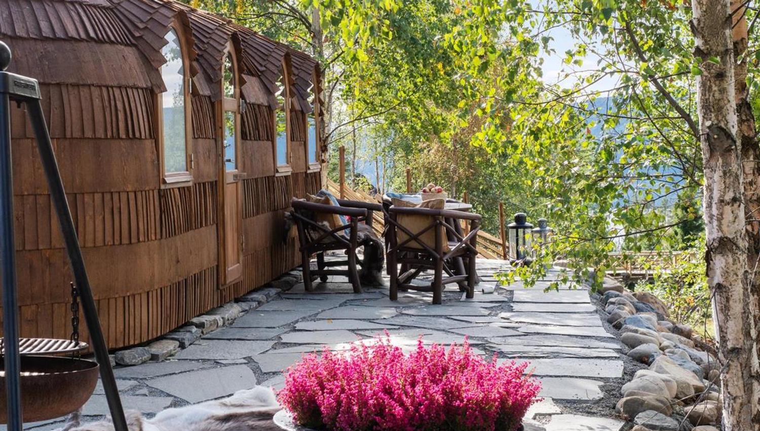 Outdoor area with stone‑slab walkway, table, and lush green trees.