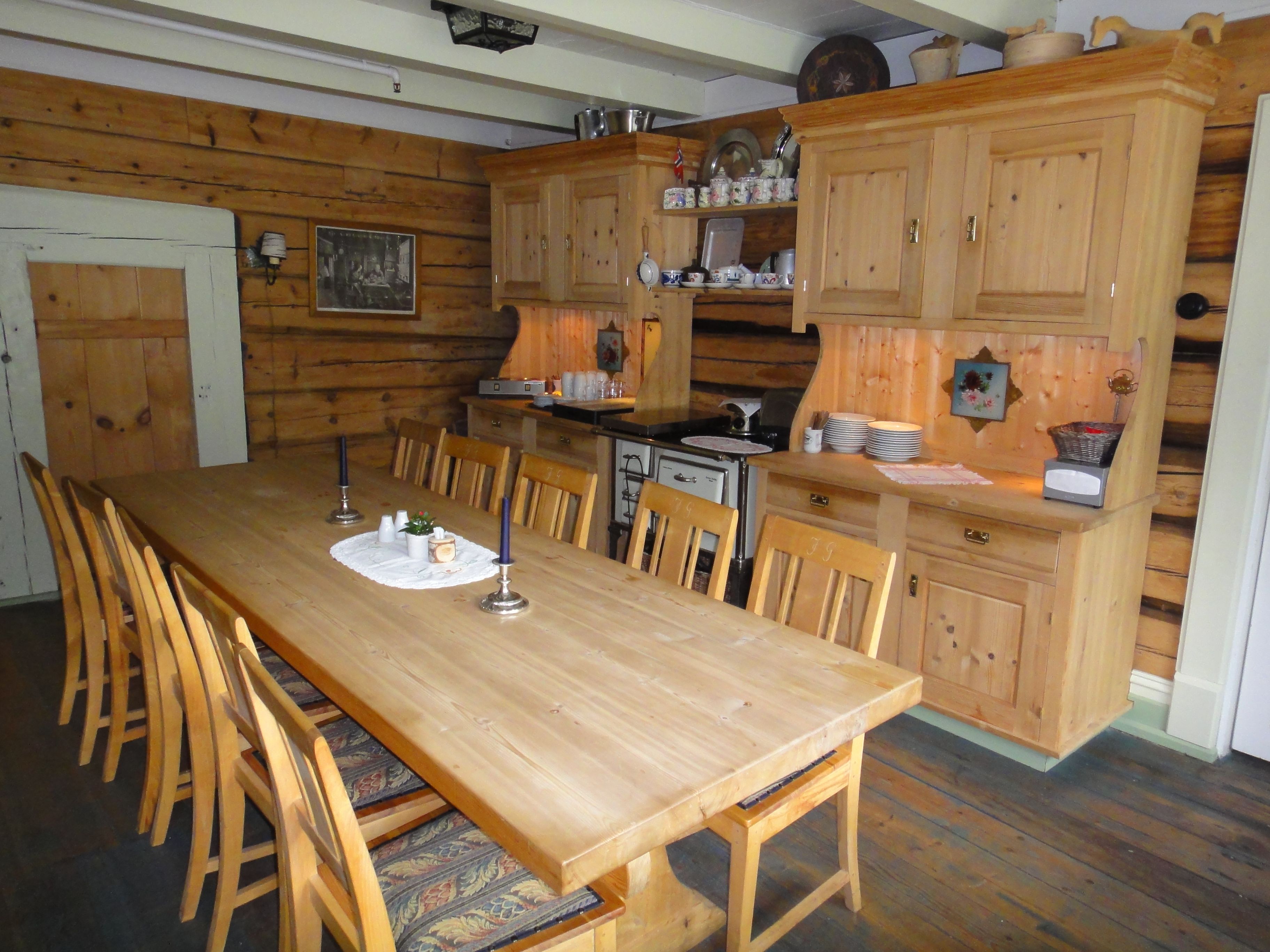 Heimekoseleg matsal med tømmerveggar, langbord og tradisjonell innreiing på Jaunsen Gjestgjevarstad i Hardanger.