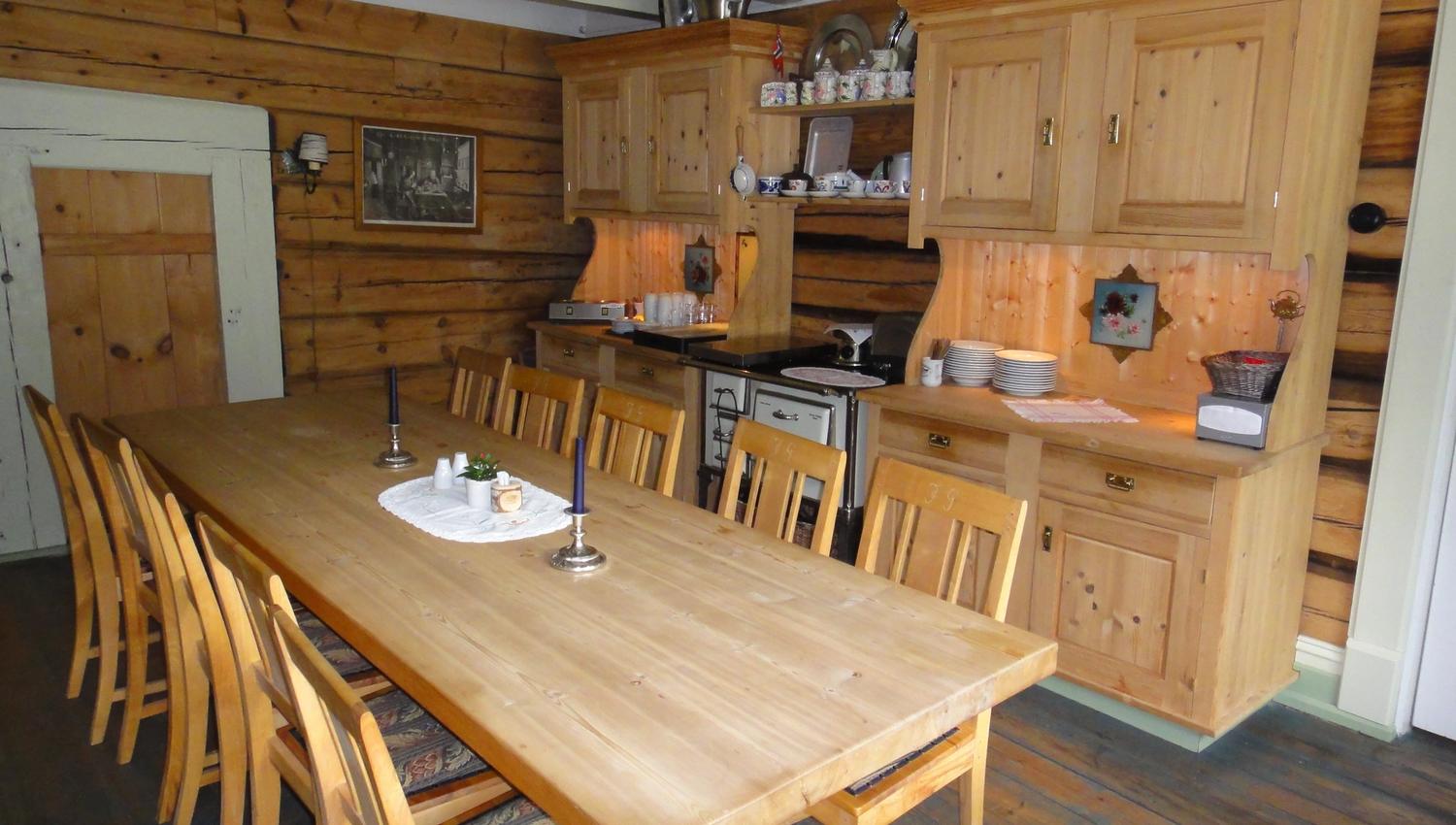 Homely dining area with log walls, long wooden table and traditional interior at Jaunsen Guesthouse in Hardanger, Norway.