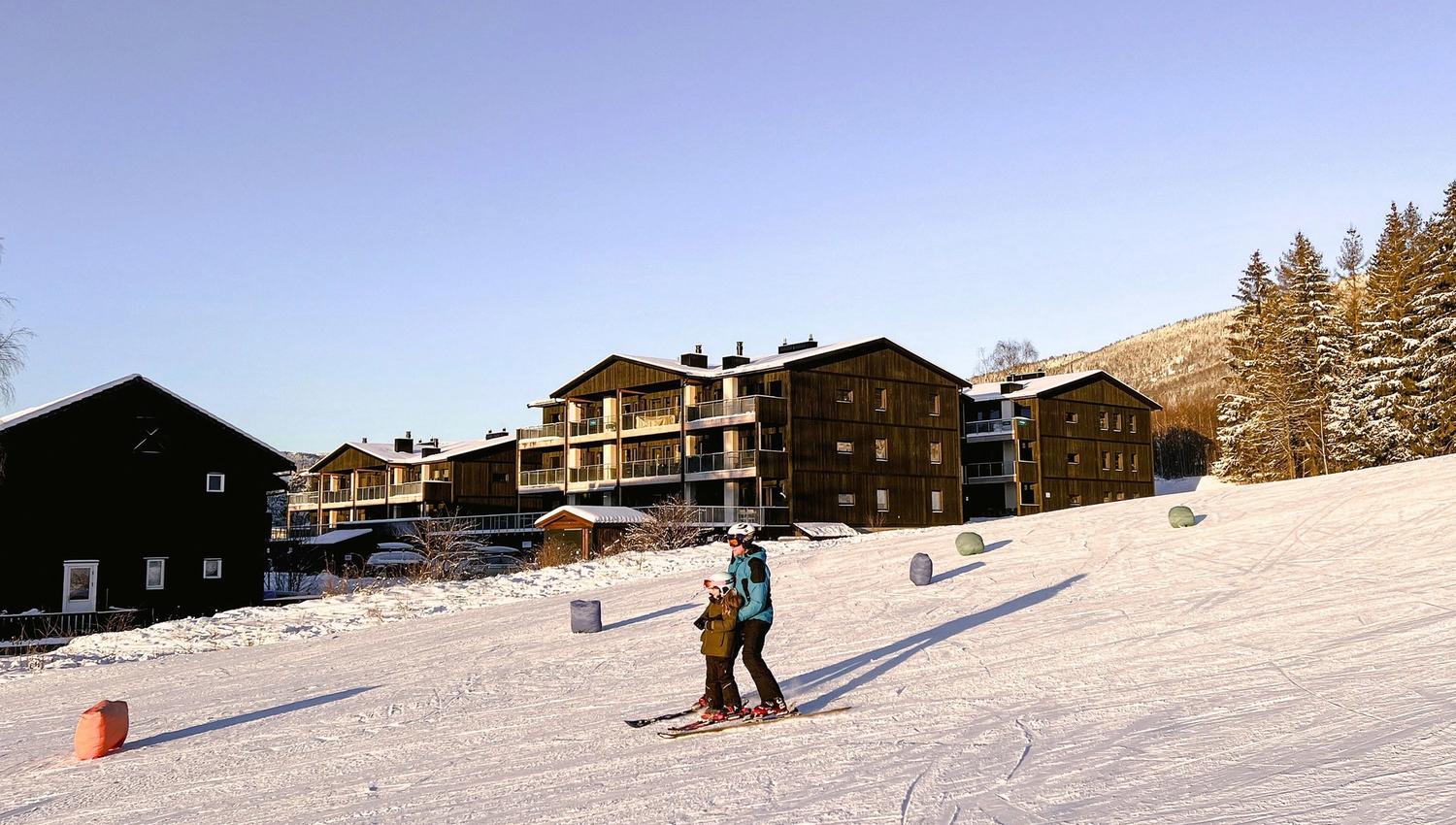 A person and a child skiing in the snow.