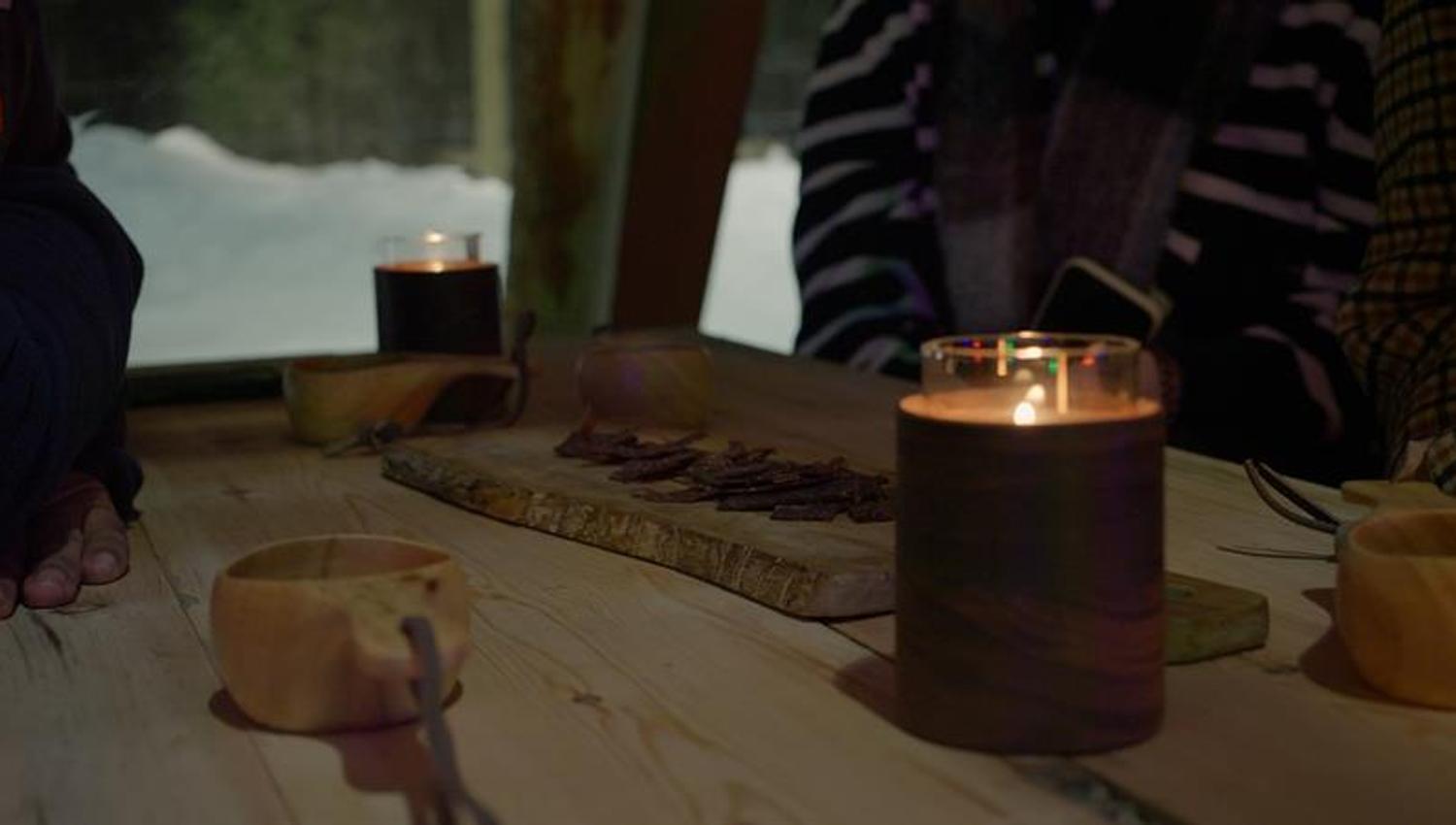 food on a tray with a candle light and a wooden cup