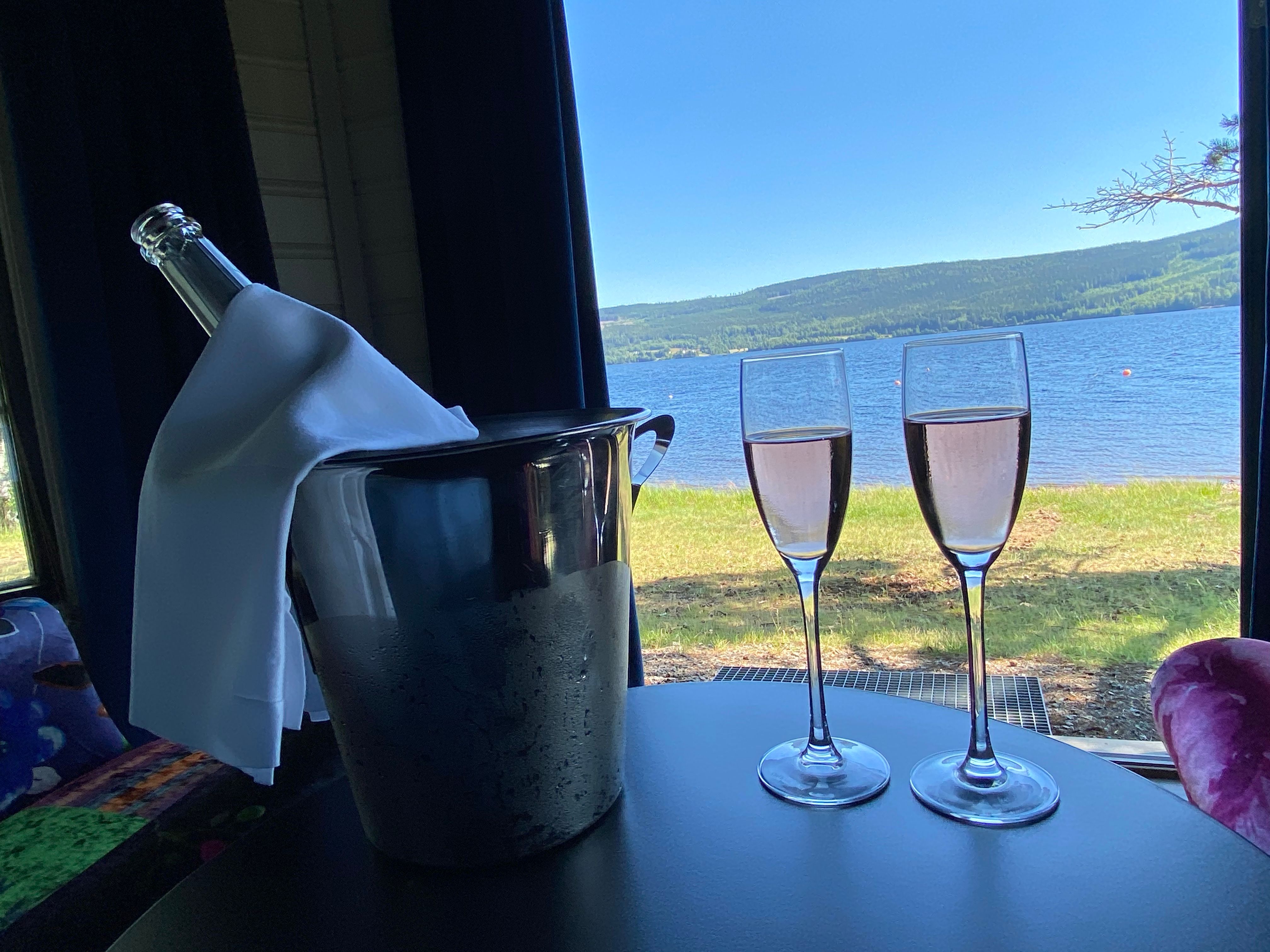 2 glass med med rosa drikke på et bord med utsikt mot en sjø
