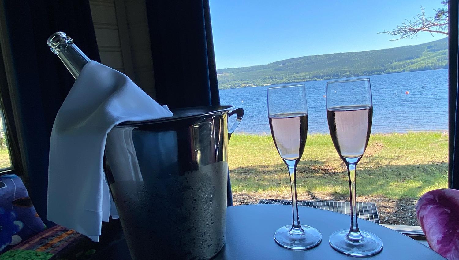 2 glass med med rosa drikke på et bord med utsikt mot en sjø