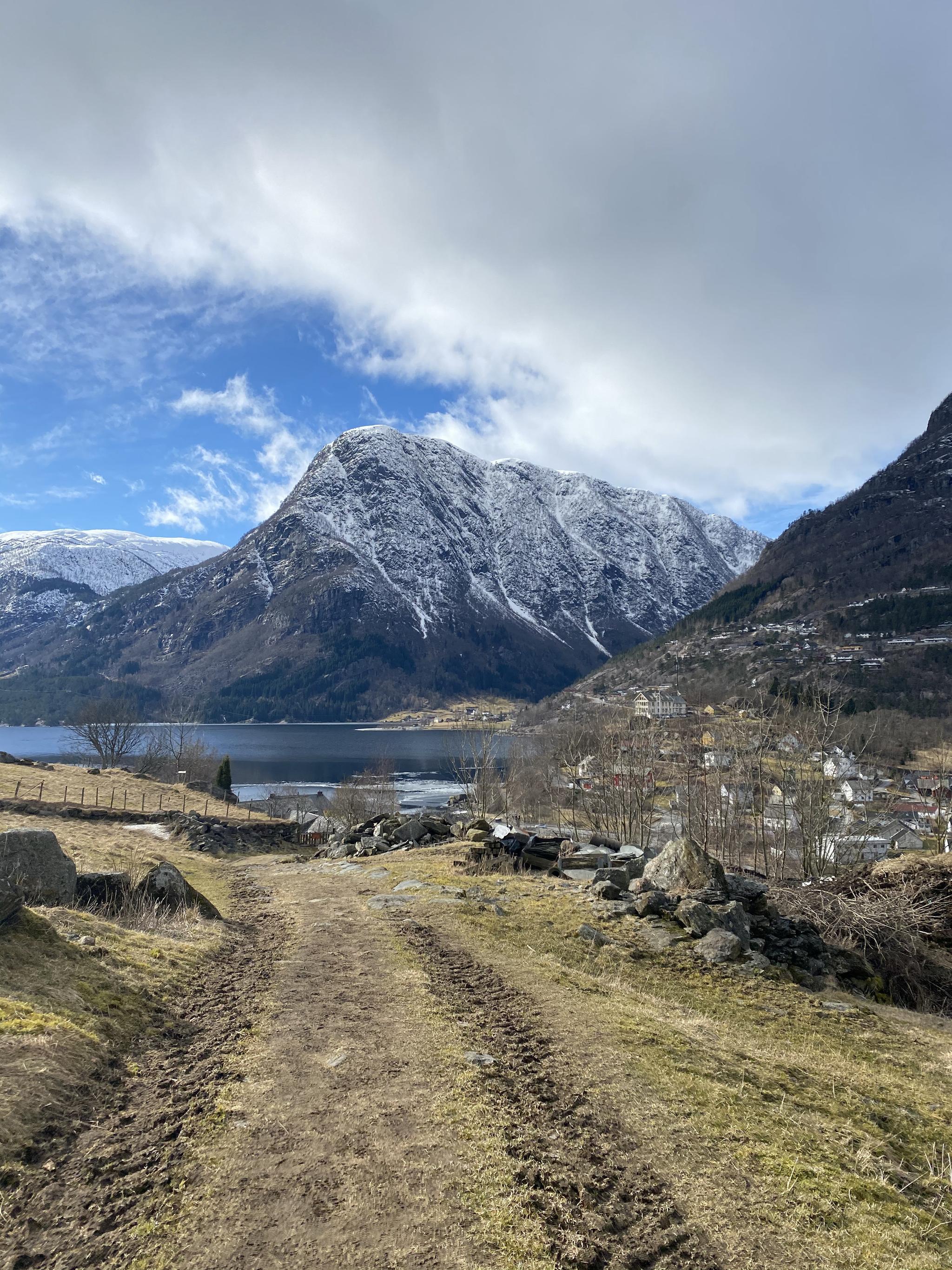 Utsikt frå kulturstien Hjøllo–Mannsåker over fjordlandskapet i Hardanger, med snødekte fjell og blå himmel.
