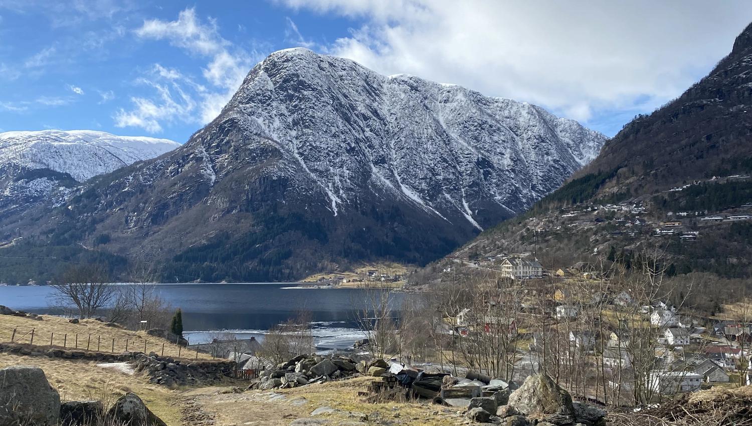 Utsikt frå kulturstien Hjøllo–Mannsåker over fjordlandskapet i Hardanger, med snødekte fjell og blå himmel.