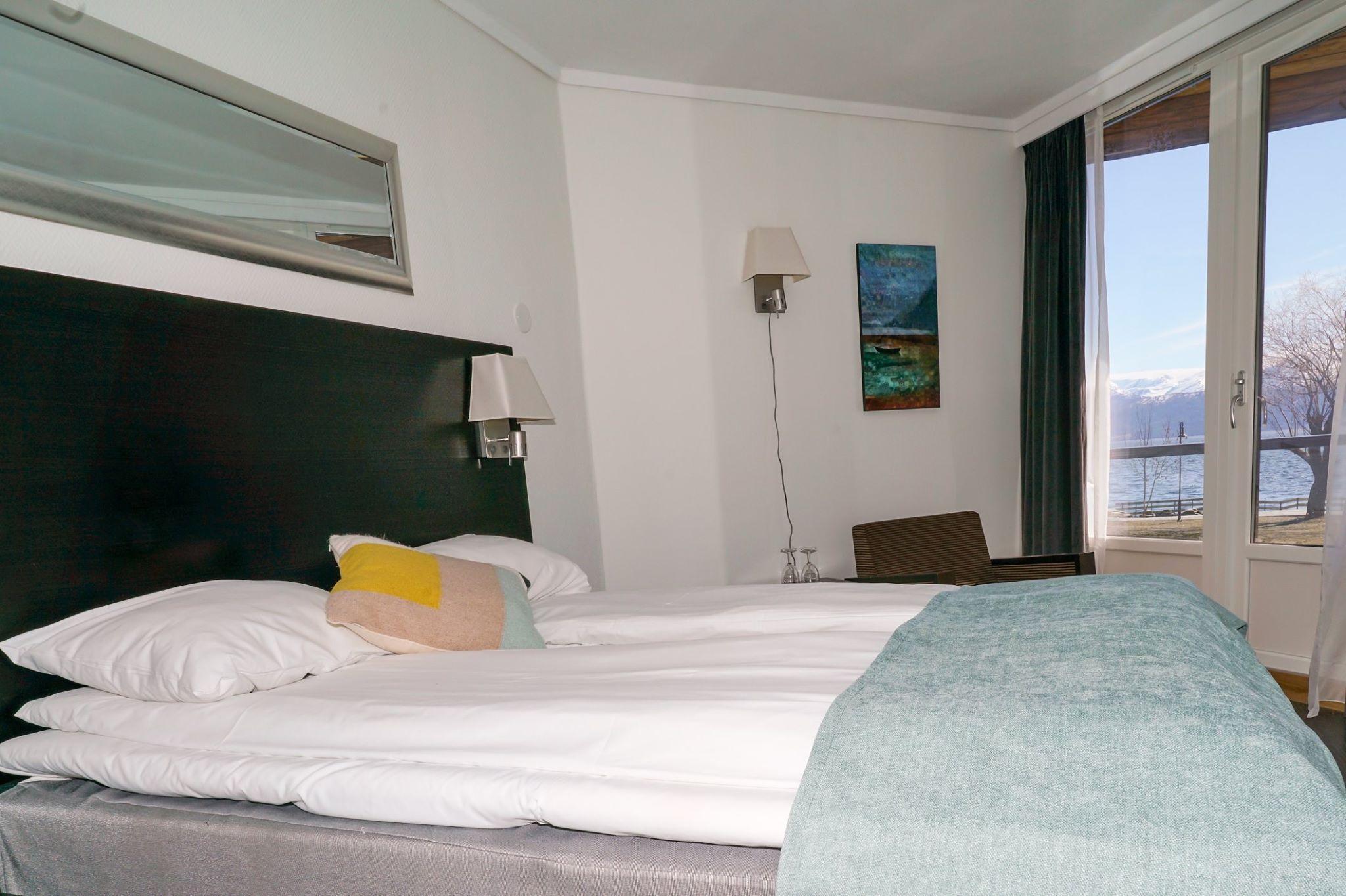 Koselig hotellrom med dobbeltseng og panoramautsikt over fjorden.