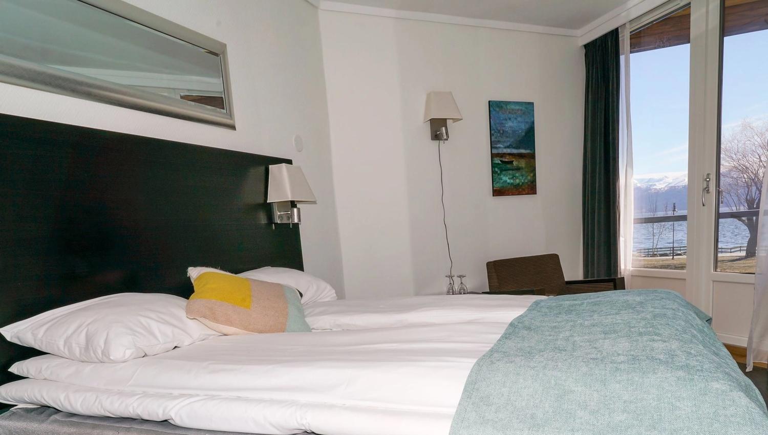 Koselig hotellrom med dobbeltseng og panoramautsikt over fjorden.