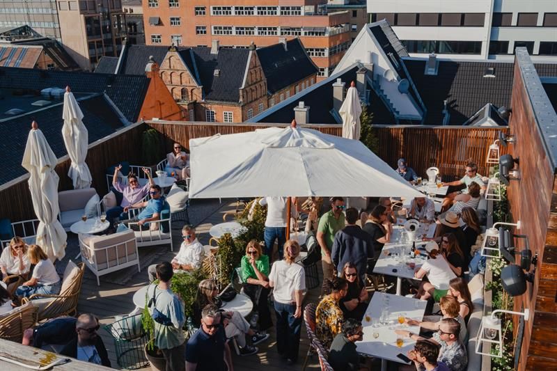 Takterrassen har sittegrupper, parasoller og beplantning, med utsikt over nærliggende bygårder. Området er tilrettelagt for servering og sosialt opphold i sesong.