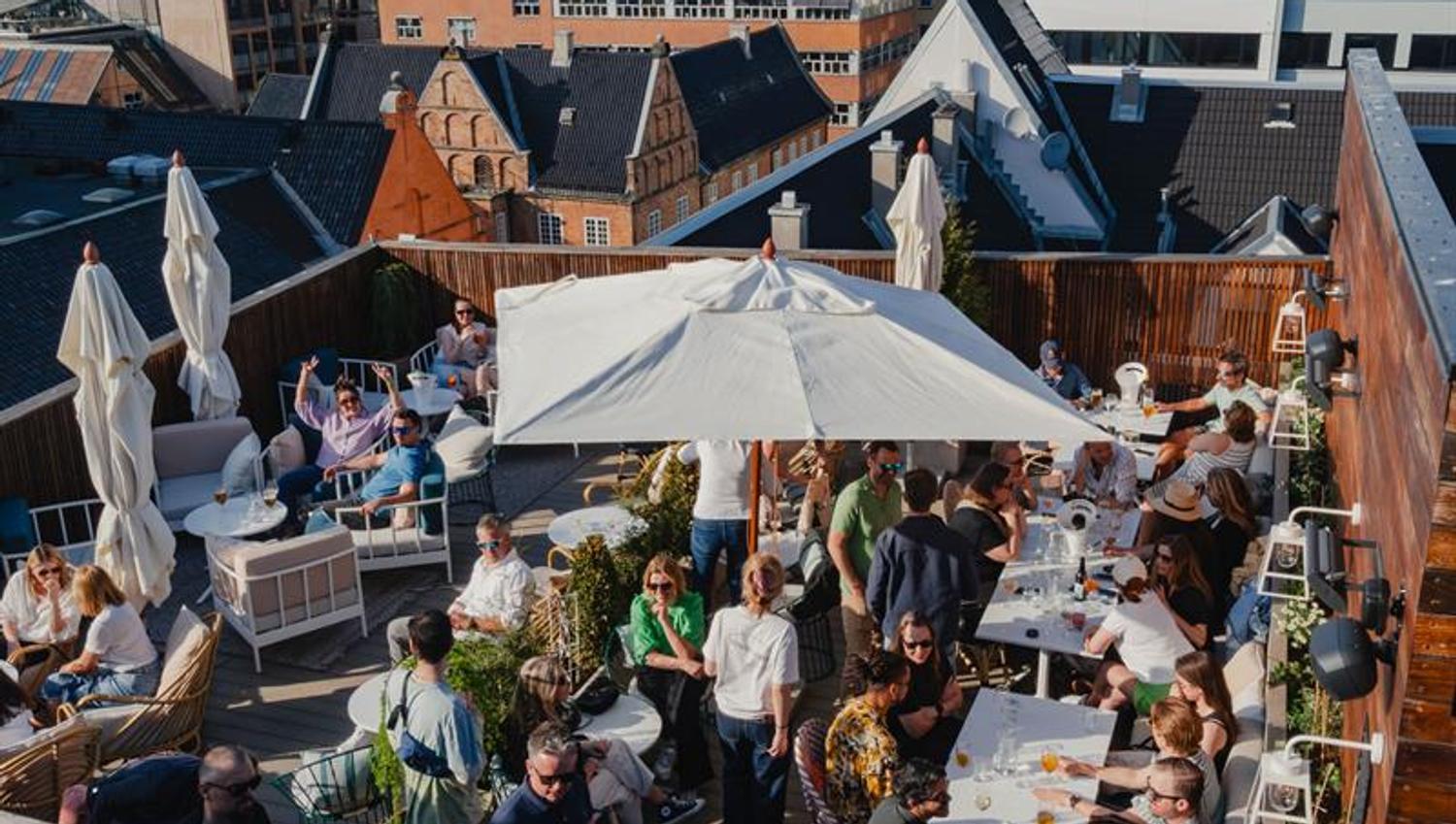 Takterrassen har sittegrupper, parasoller og beplantning, med utsikt over nærliggende bygårder. Området er tilrettelagt for servering og sosialt opphold i sesong.