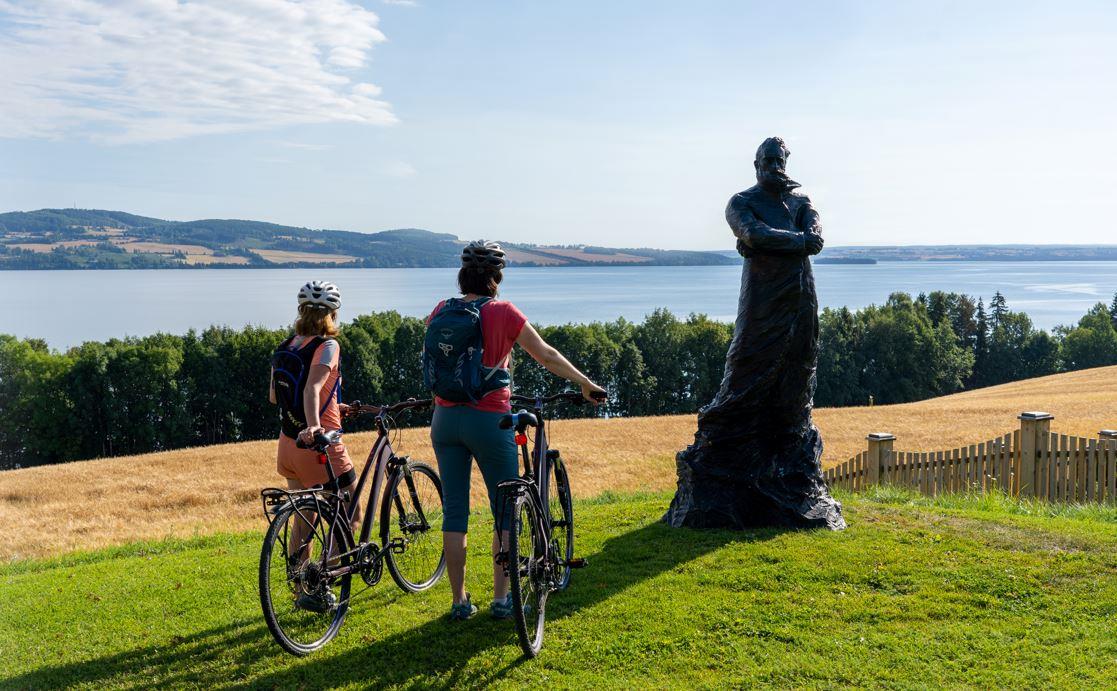 Peder Balke-senteret på Kapp i Østre Toten. Mjøstråkk-syklister nyter Mjøsutsikten ved Peder Balke statue.