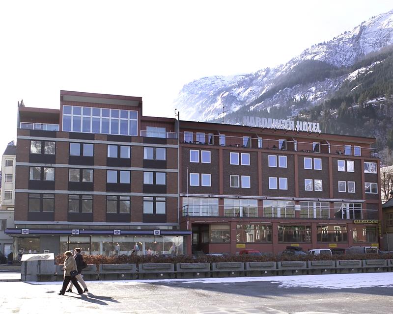 Hardanger Hotel om vinteren med snødekte fjell i bakgrunnen.