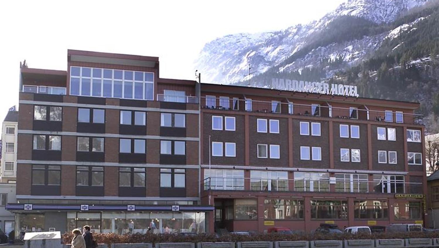 Hardanger Hotel om vinteren med snødekte fjell i bakgrunnen.