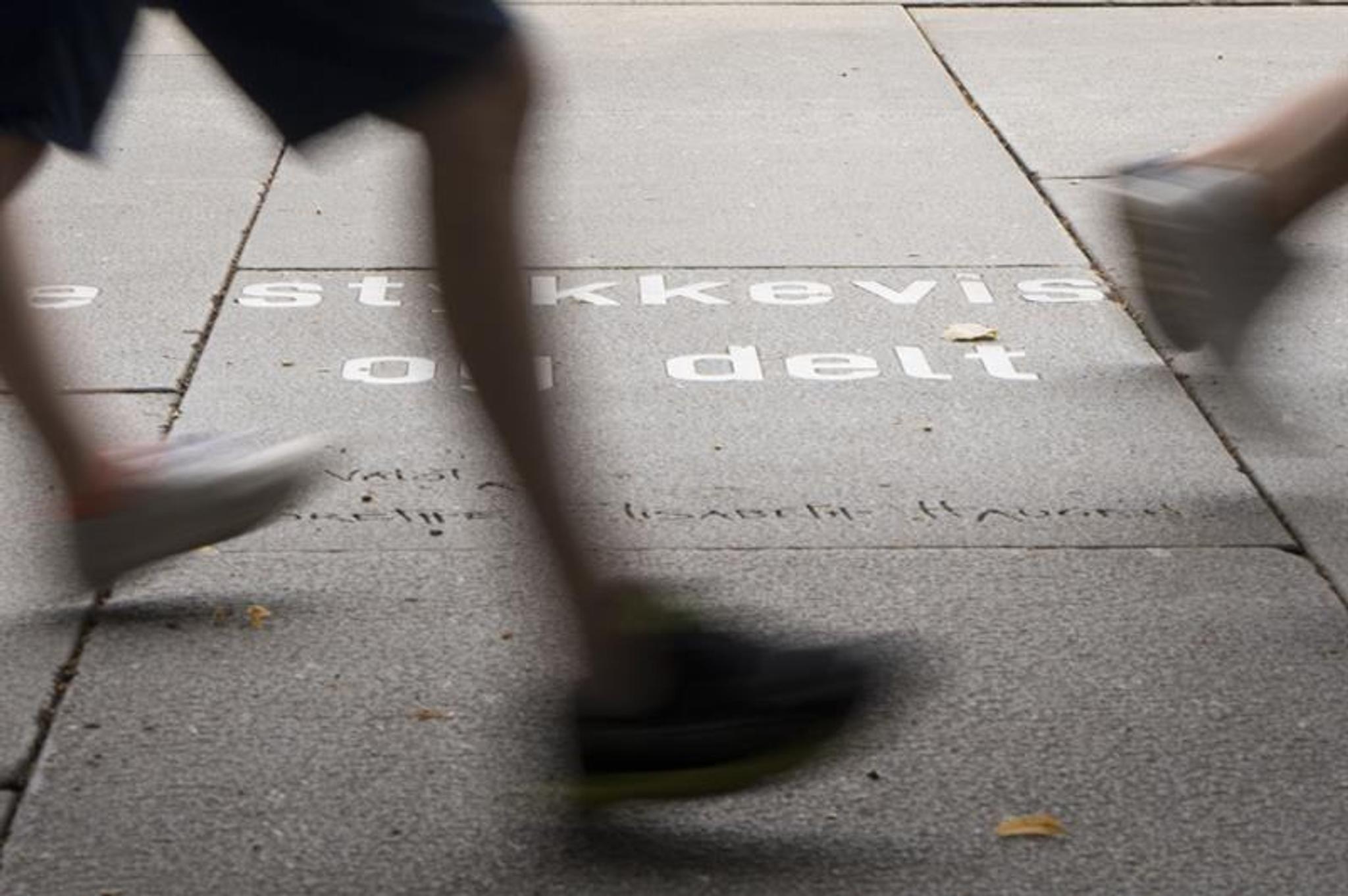 Feet walking past an Ibsen quote on the ground.