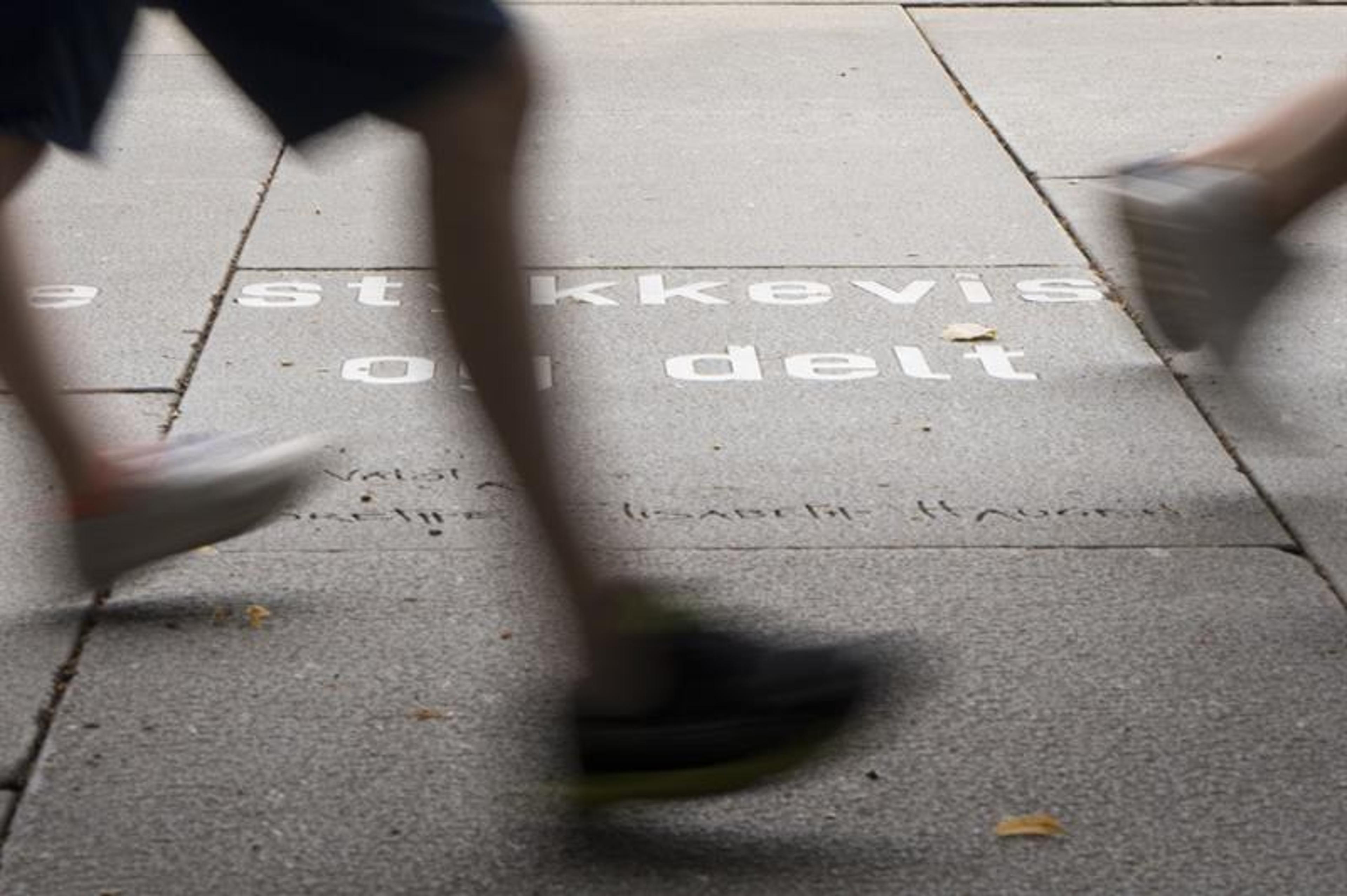 Feet walking past an Ibsen quote on the ground.