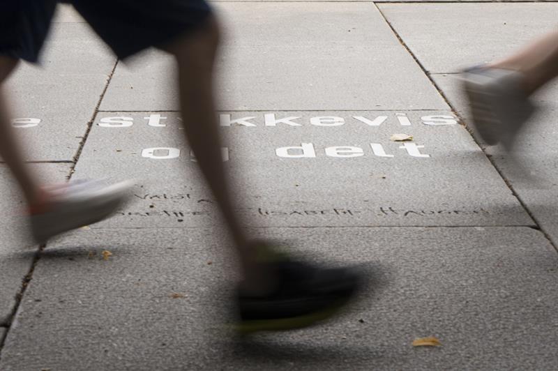 Feet walking past an Ibsen quote on the ground.