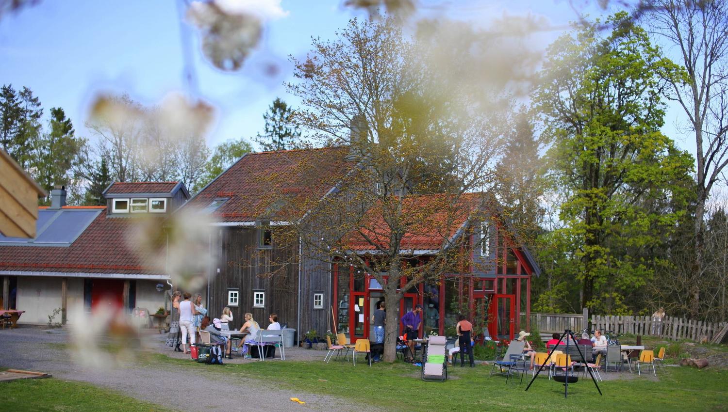 Farmhouse with house, green garden, trees and people