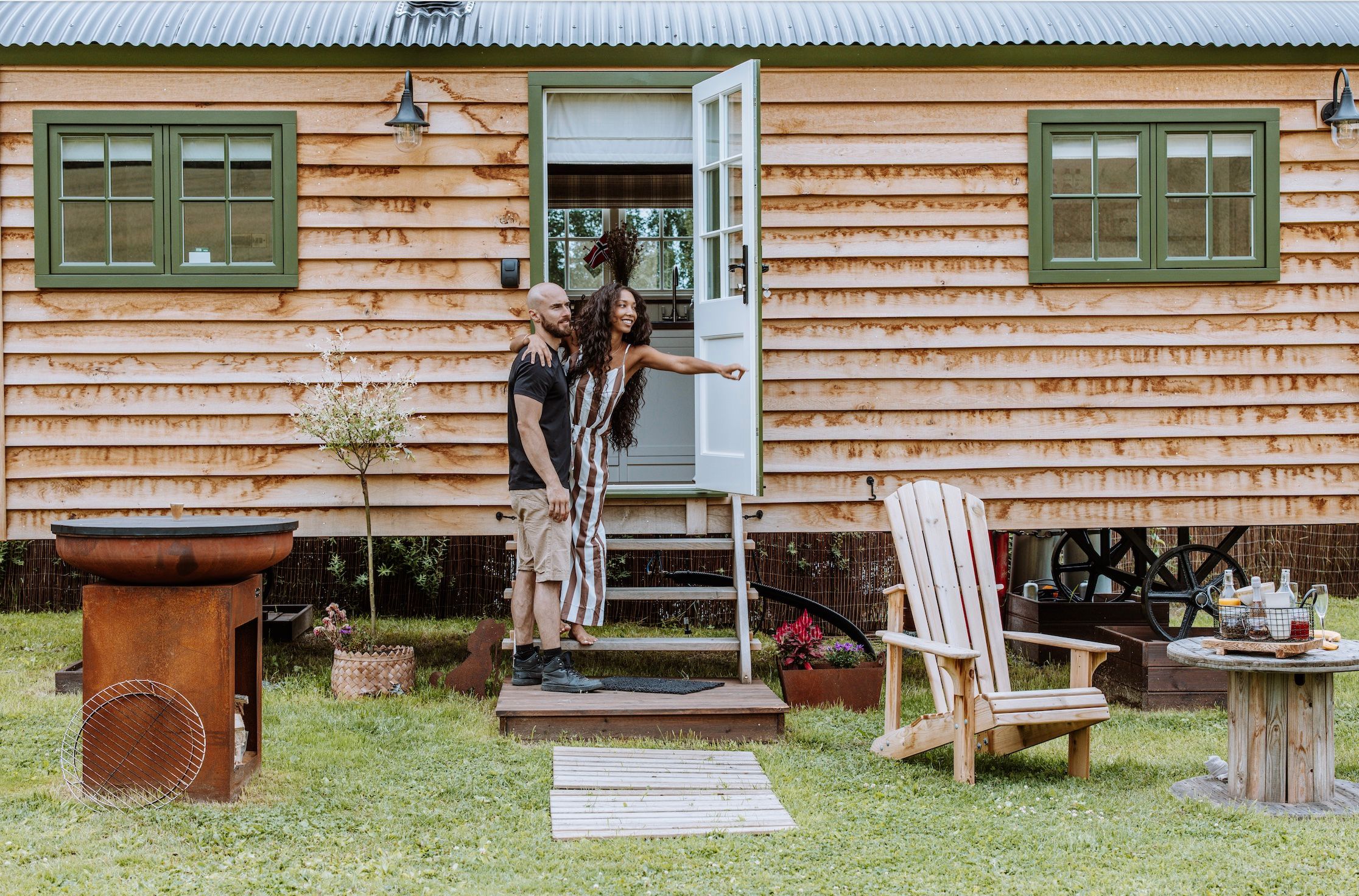 Par foran Shepherds Hut - lite trehus med grønne vinduer og stoler foran