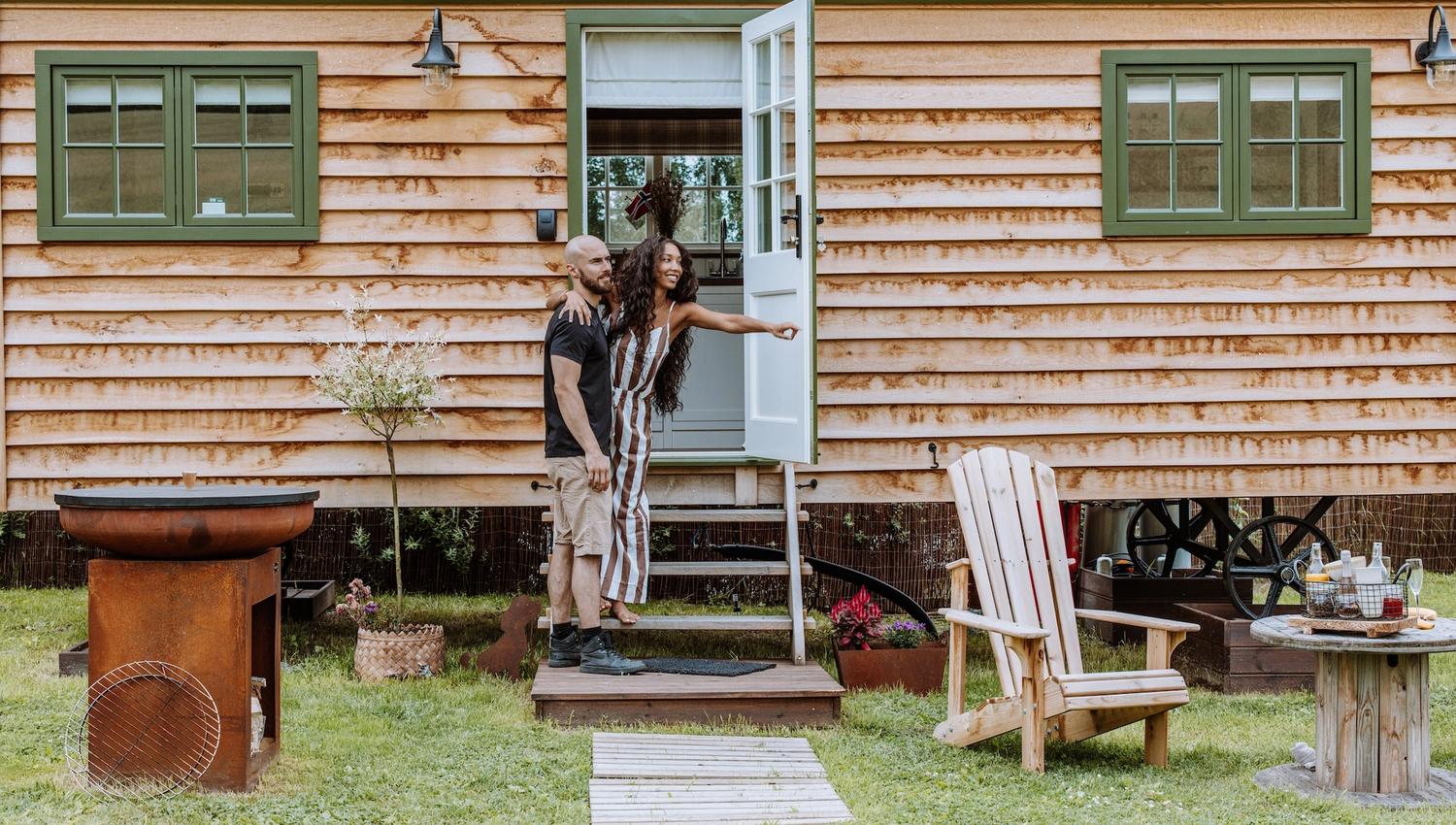 Par foran Shepherds Hut - lite trehus med grønne vinduer og stoler foran