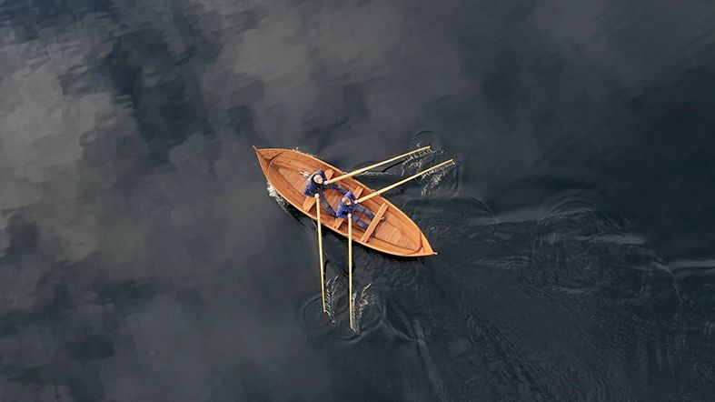 Aerial view of a man rowing a traditional rowboat on Hardangerfjord.
