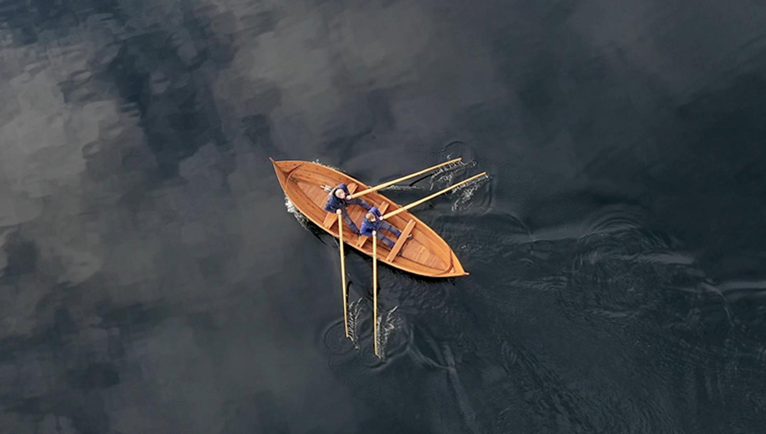 Aerial view of a man rowing a traditional rowboat on Hardangerfjord.