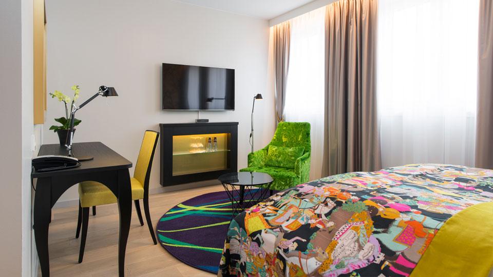 Colourful room with a double bed, TV and desk