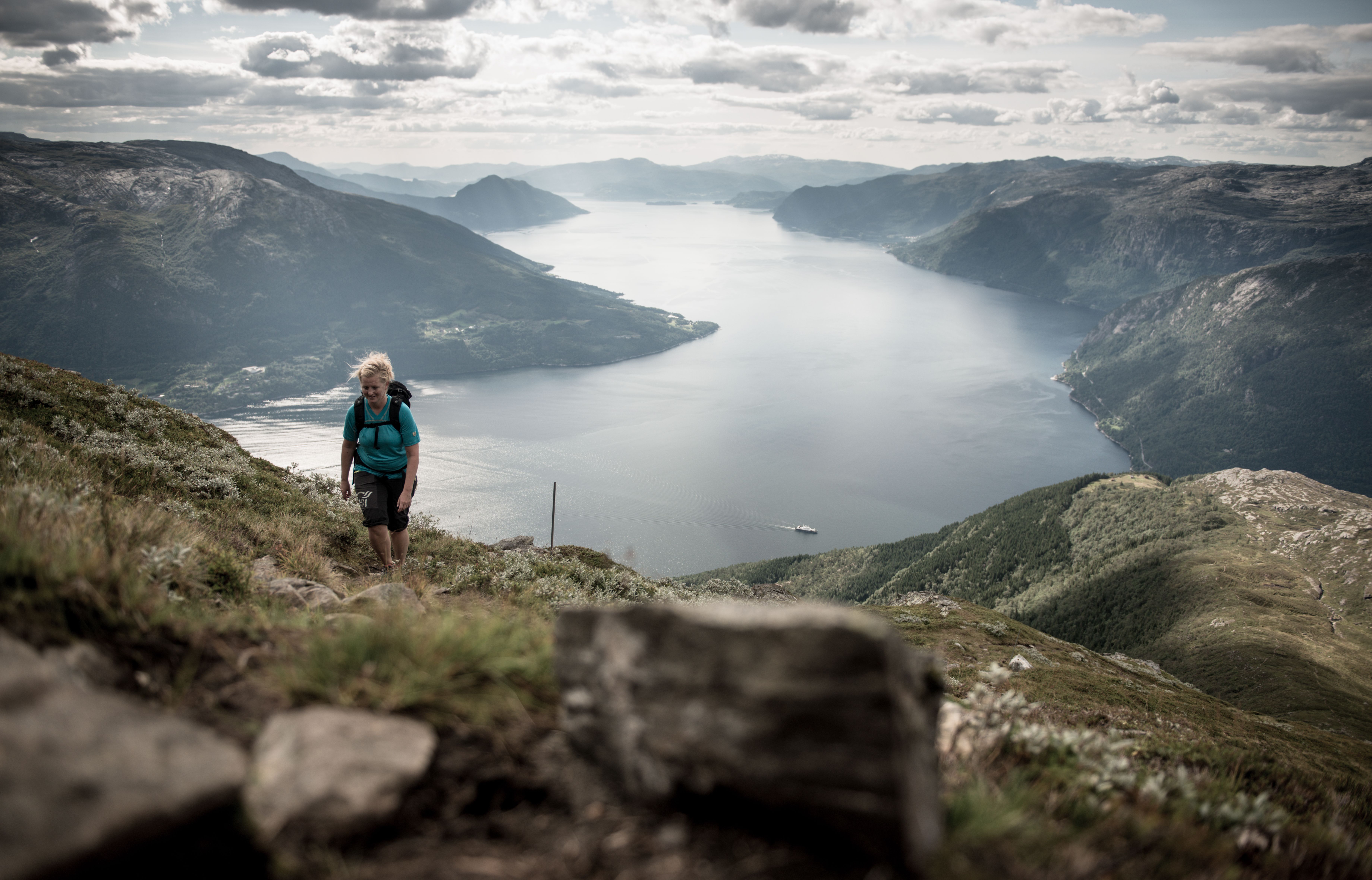 Ein turgåar stig oppover fjellsida med Hardangerfjorden i bakgrunnen.