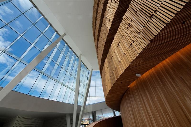 Interiørbilde av trappesats i tre og store vinduer mot den blå himmelen på motsatt side.