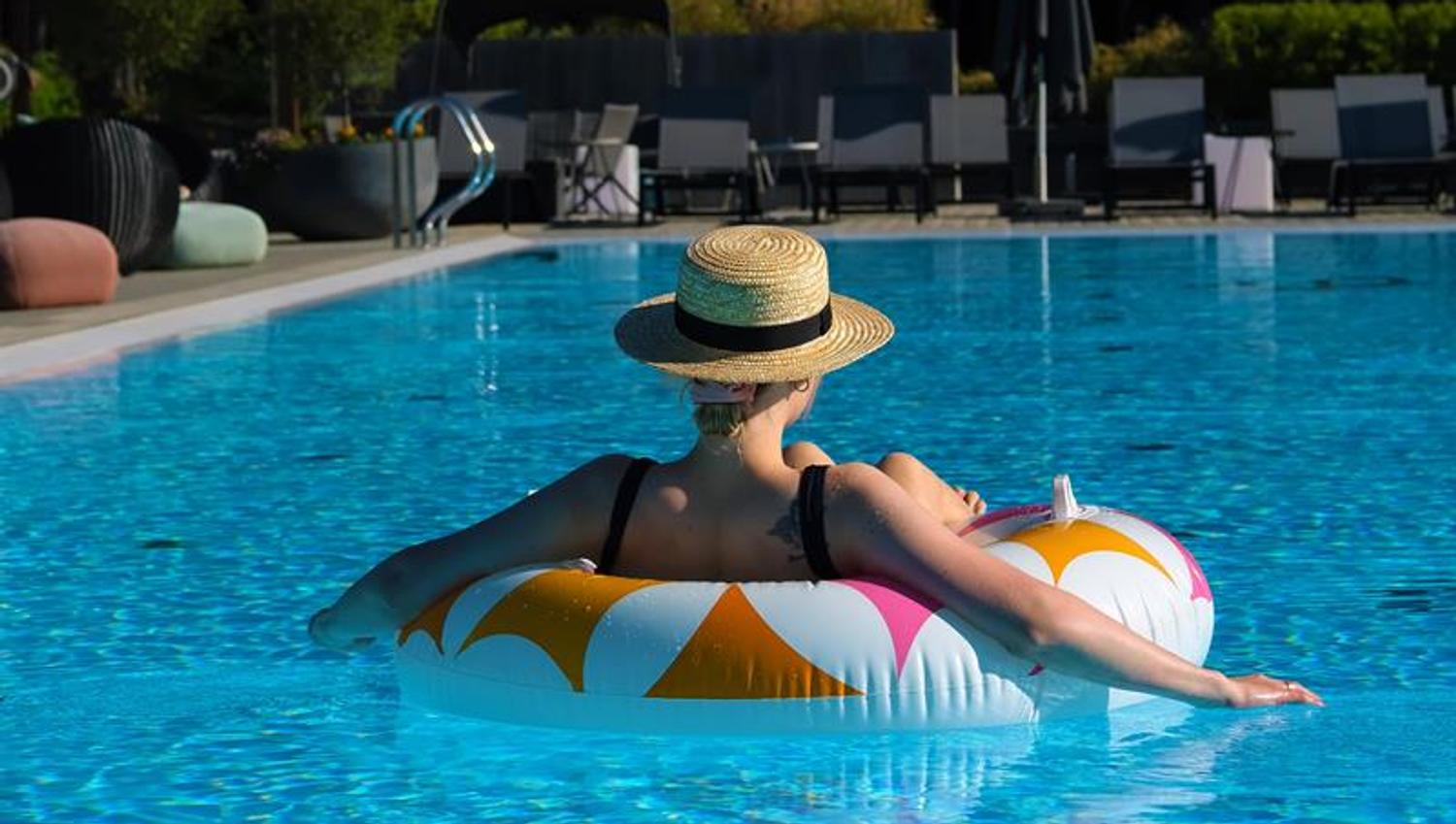 Utebasseng sommer The Well, dame med solhatt på badering