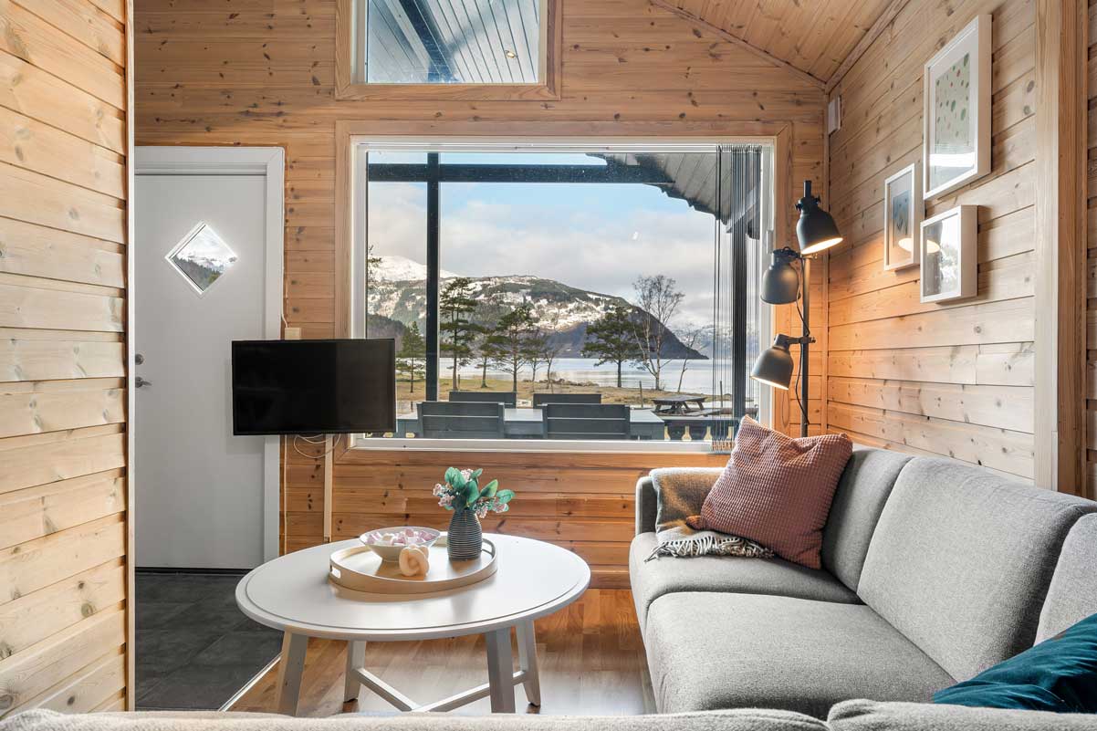 Innvendig bilete av ei hytte på Mikkelparken Ferietun, med panoramautsikt over fjorden og snødekte fjell.