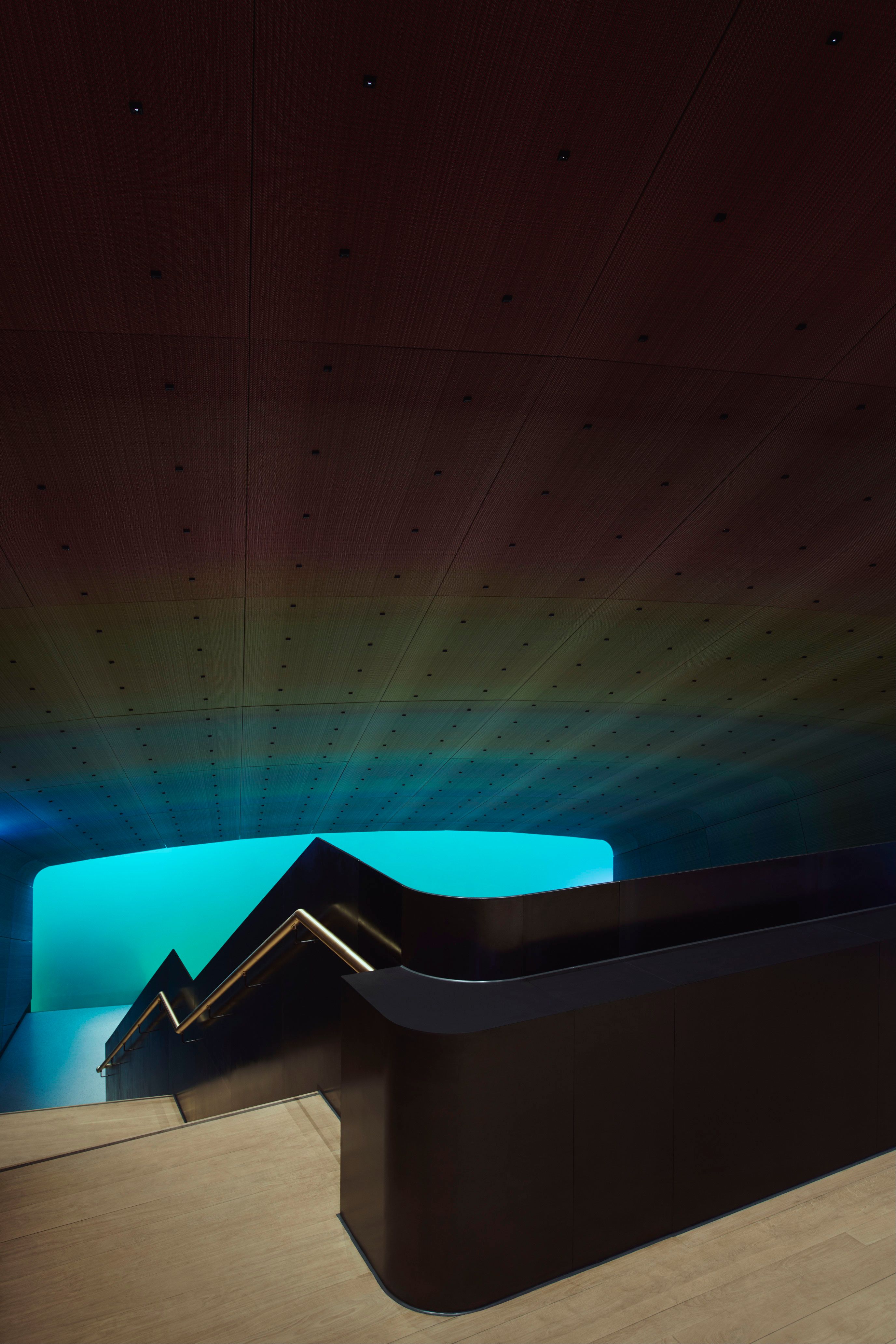 Stairs down to the restaurant, dark room, with turquoise light from the sea shining towards me.