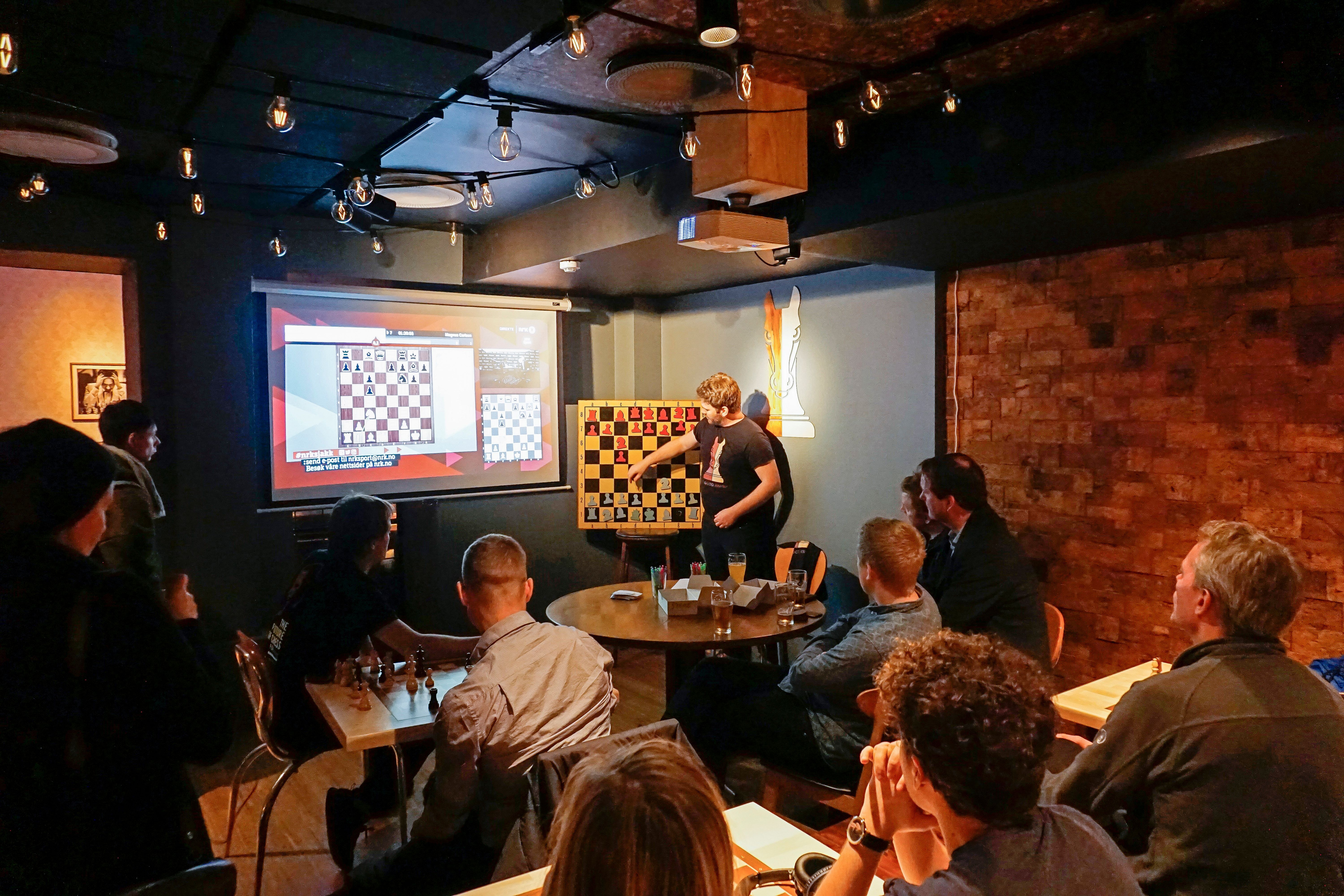 a person giving a lecture on chess in front of guests