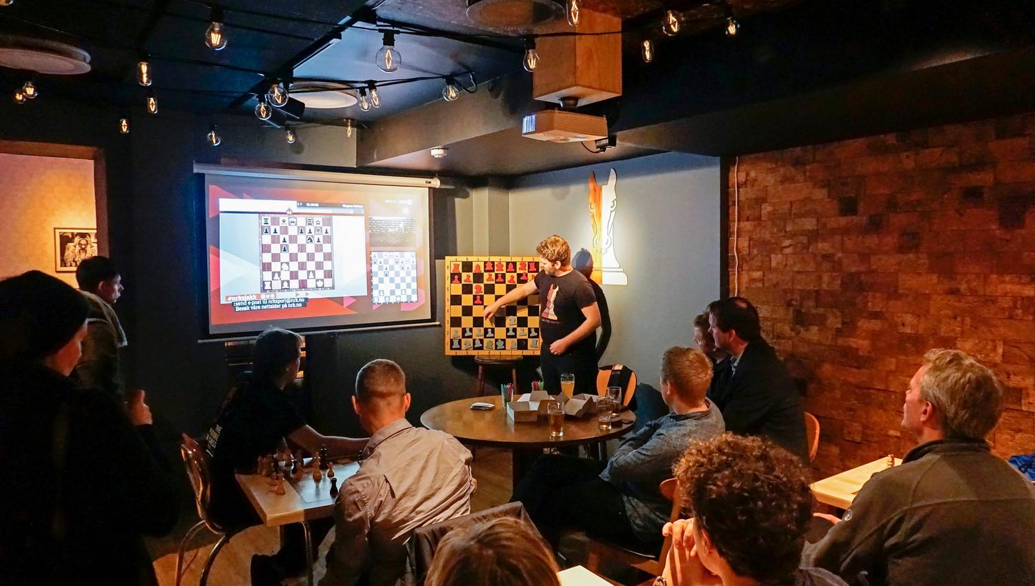 a person giving a lecture on chess in front of guests