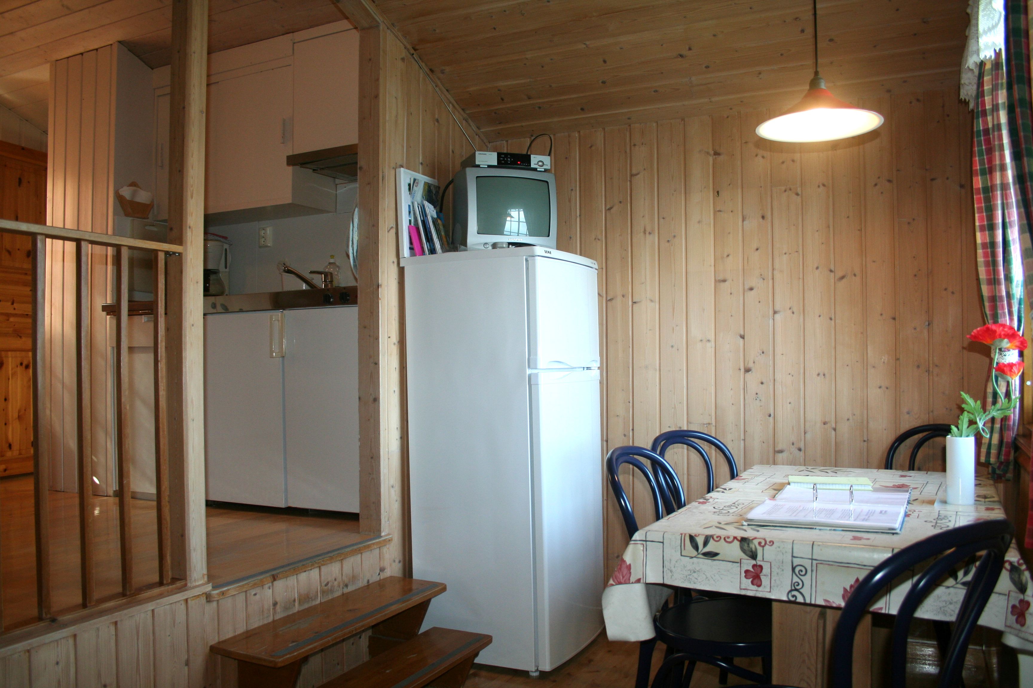 Klassisk hyttekjøkken med spisebord og TV i ei eldre hytte på Oddland Camping.