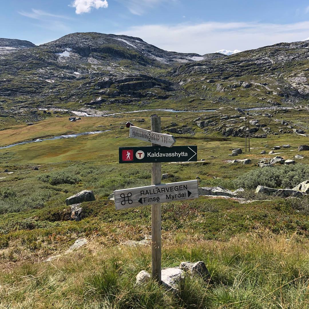 Vegskilt som viser retning mot Rallarvegen, Finse og Kaldevasshytta i vakker høgfjellsnatur.