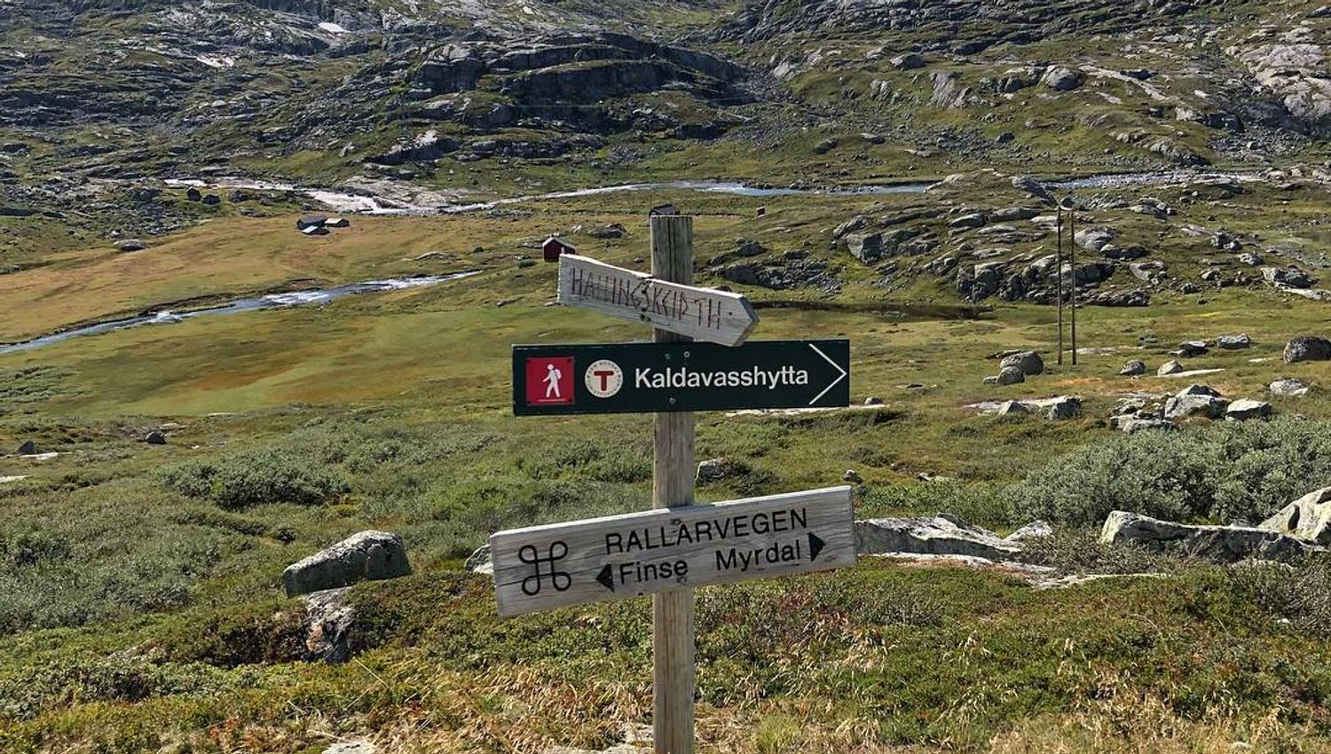 Vegskilt som viser retning mot Rallarvegen, Finse og Kaldevasshytta i vakker høgfjellsnatur.