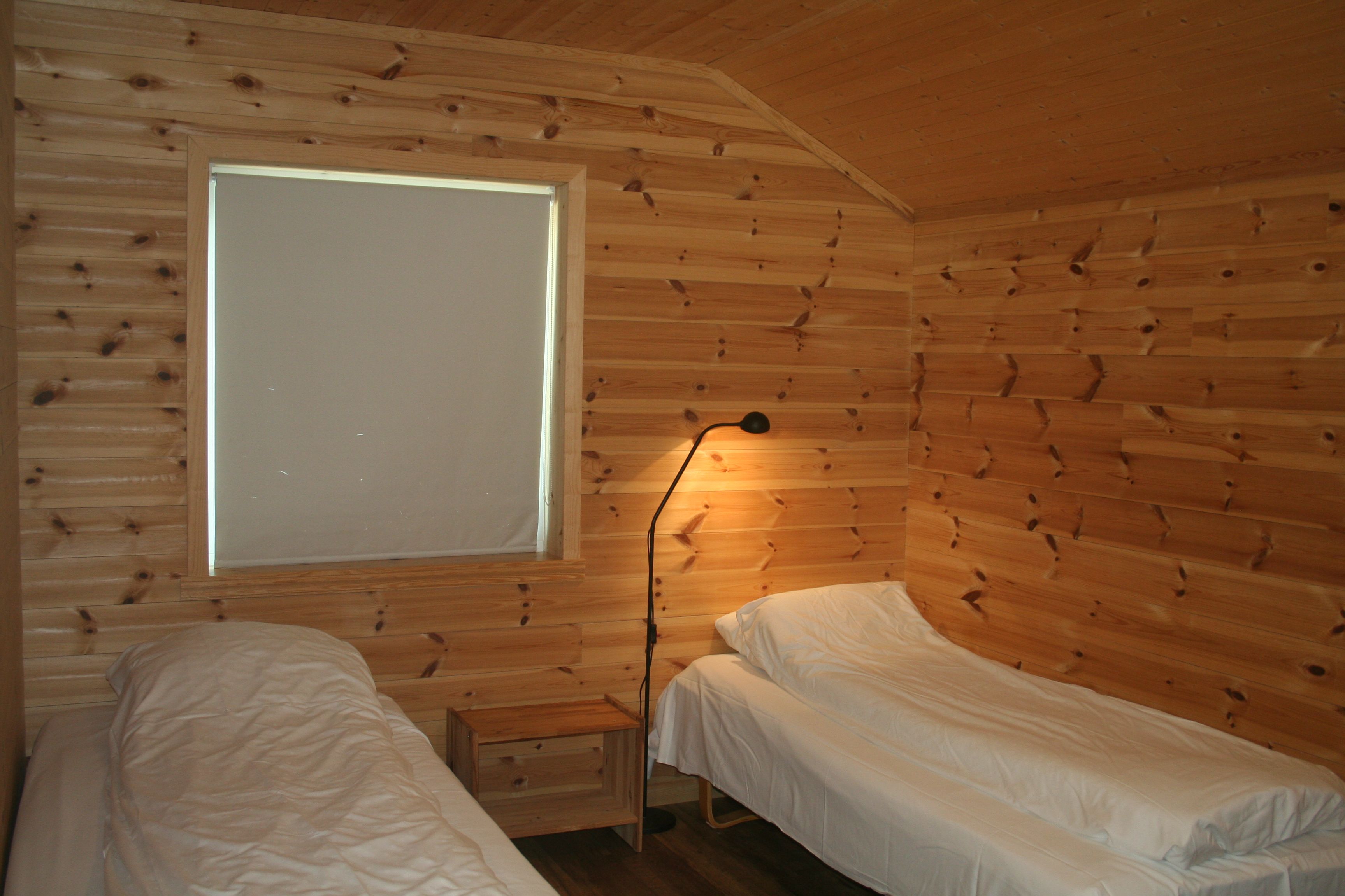 Soverom med naturleg trepanel og to enkeltsenger på Vågen Rom og Hytteutleige.