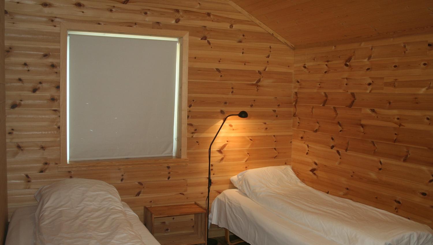 Soverom med naturleg trepanel og to enkeltsenger på Vågen Rom og Hytteutleige.