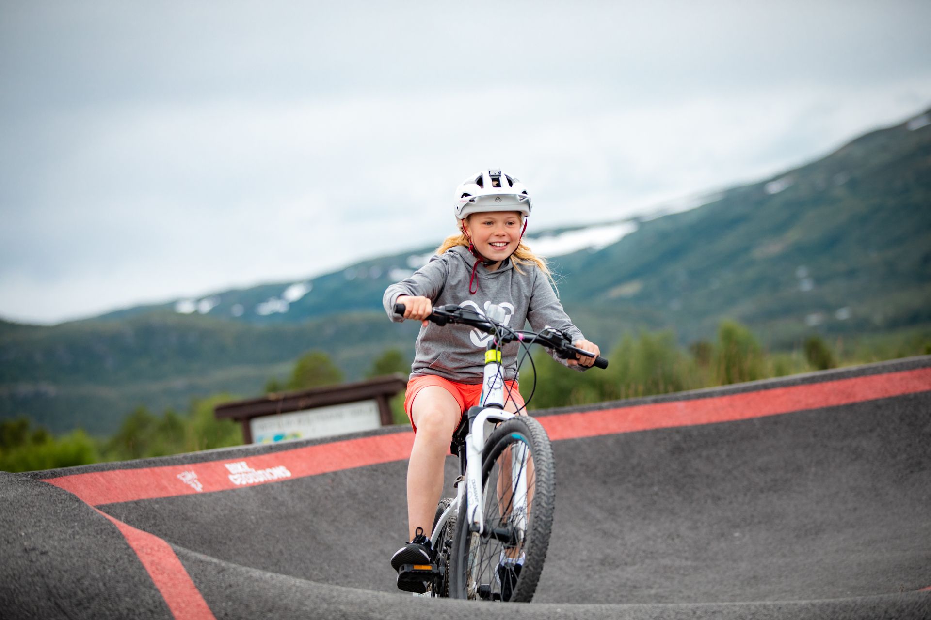 A smiling girl on a bike on the pumptrack in the Vestlia Bike Park at Geilo.