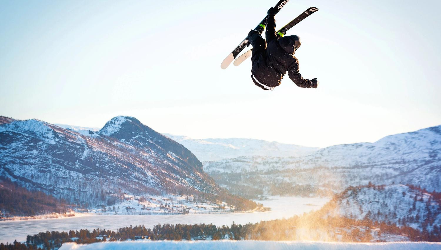 Gutt på ski flyr høyt, med utsikt over Hovden, bilde