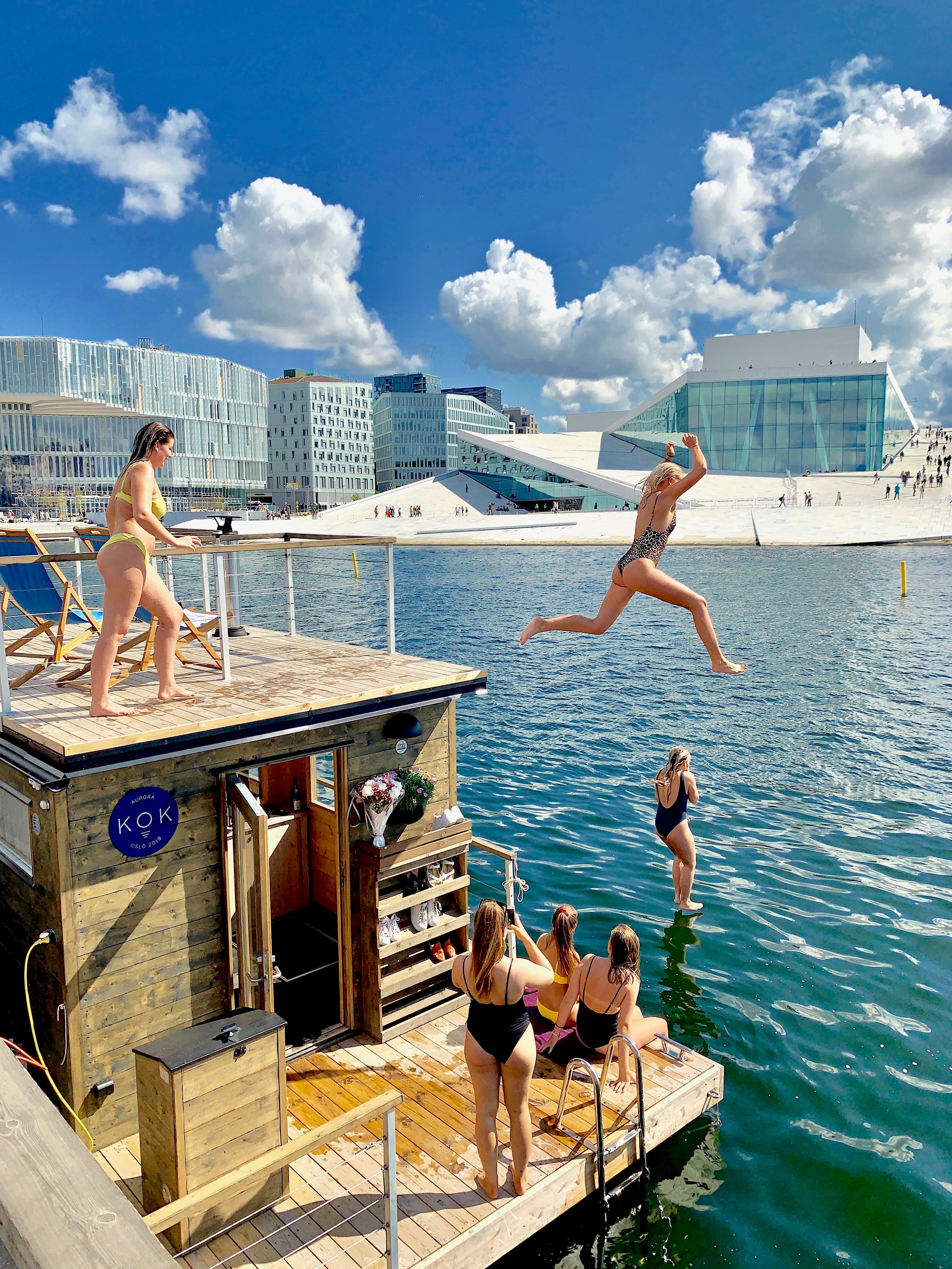 Mennesker som hopper i vannet med operaen i bakgrunnen.