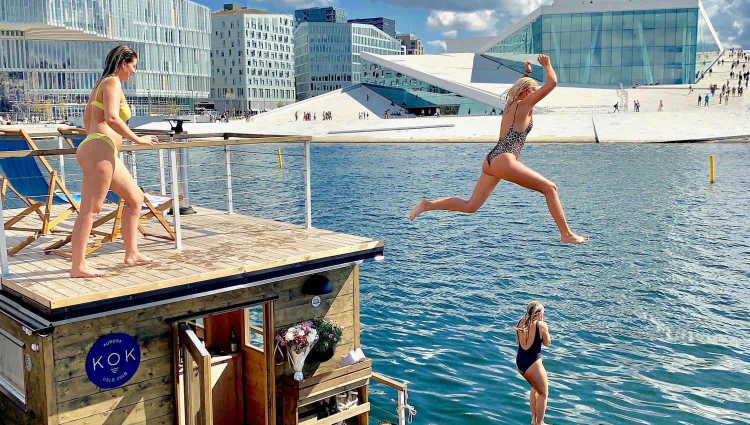 Mennesker som hopper i vannet med operaen i bakgrunnen.