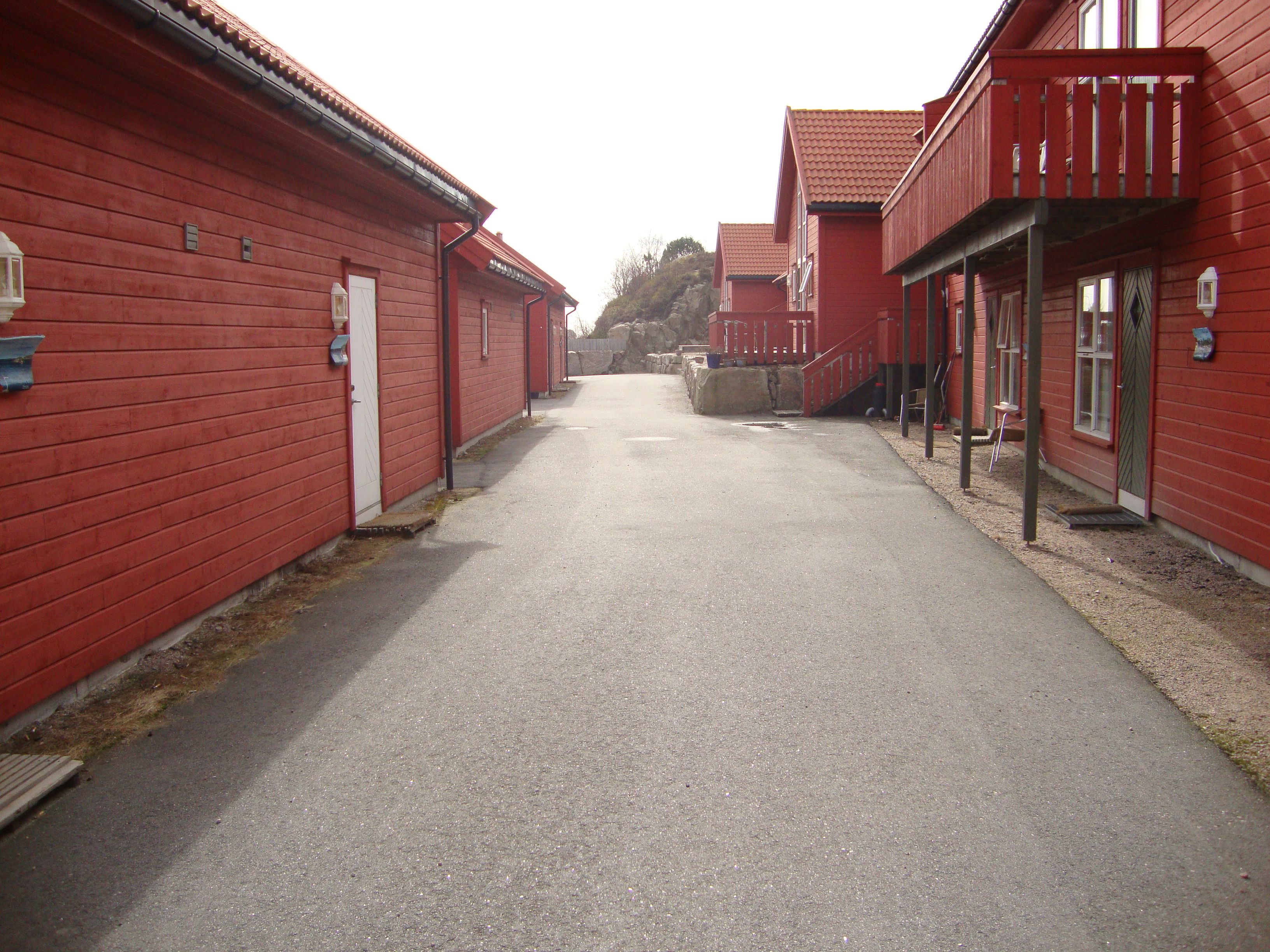 Røde hytter rekke på rad med vei i midten