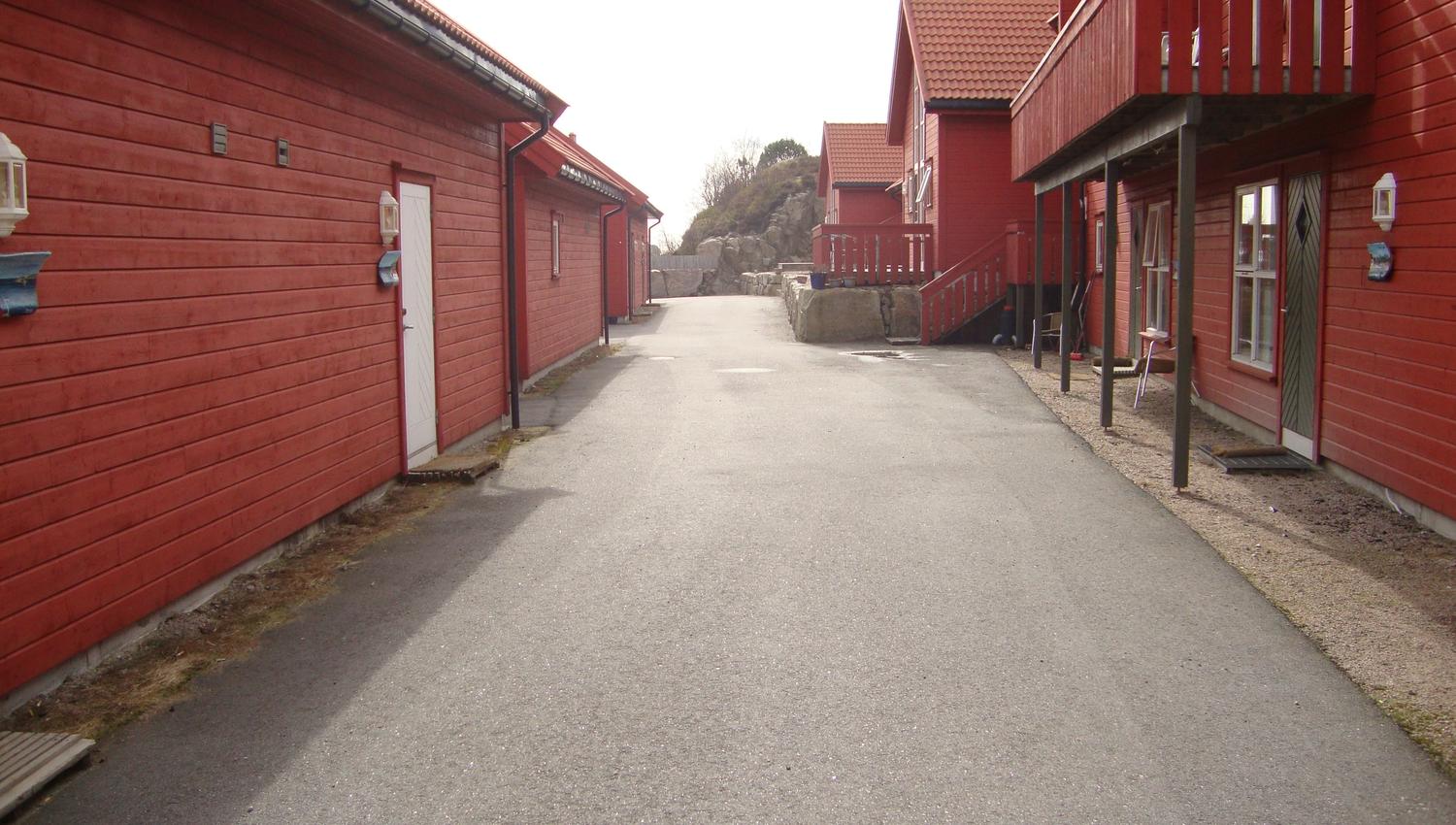 Røde hytter rekke på rad med vei i midten