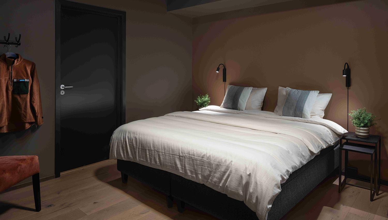Hotellrom i duse farger med stor dobbeltseng