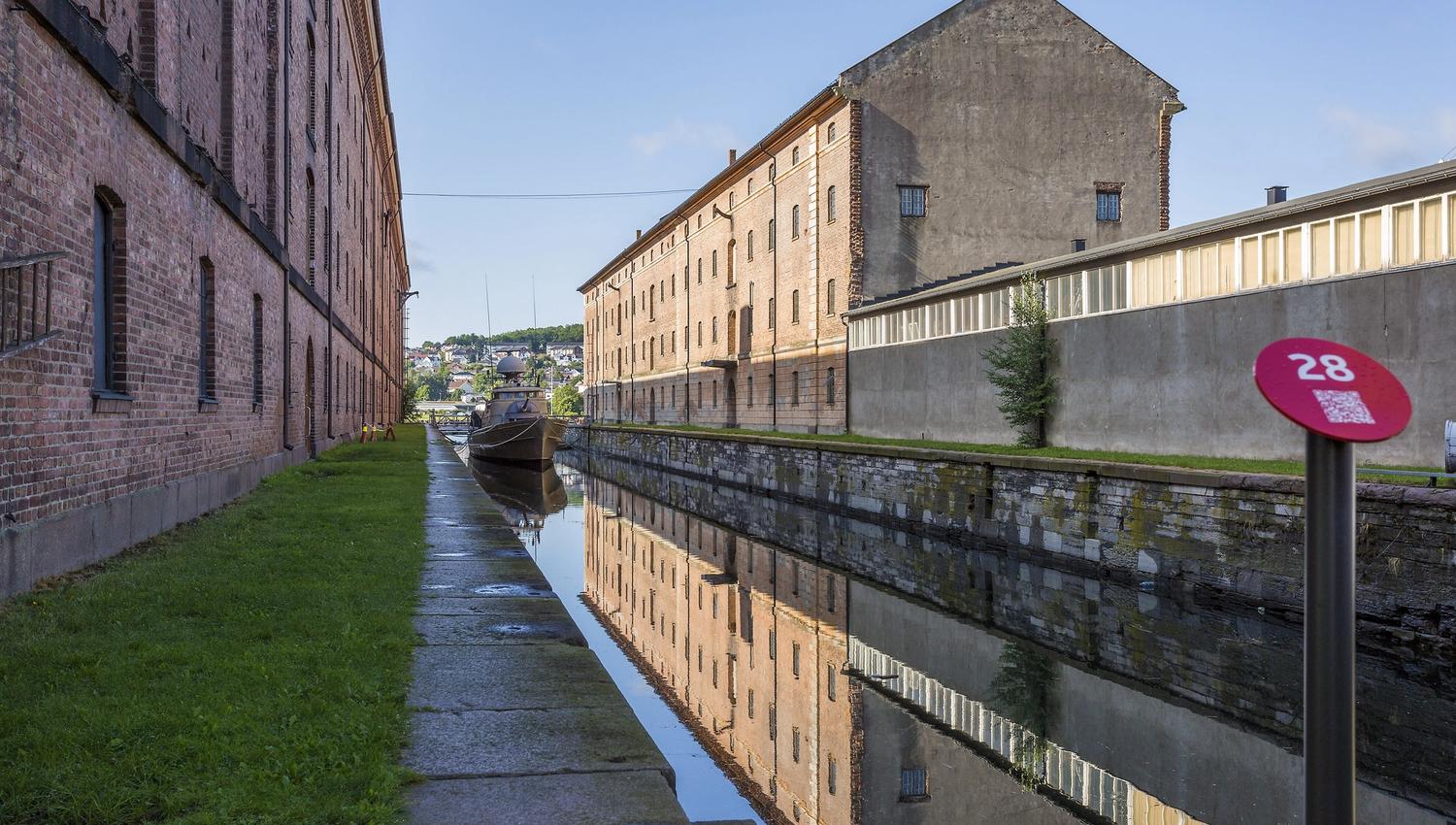 En lang kanal med vann, murbygninger på hver side og en båt ligger nederst i kanalen.