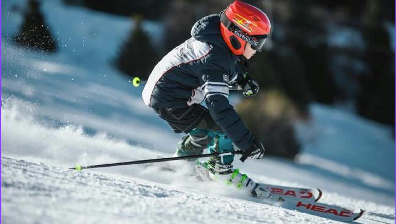Gutt med rød hjelm står slalom