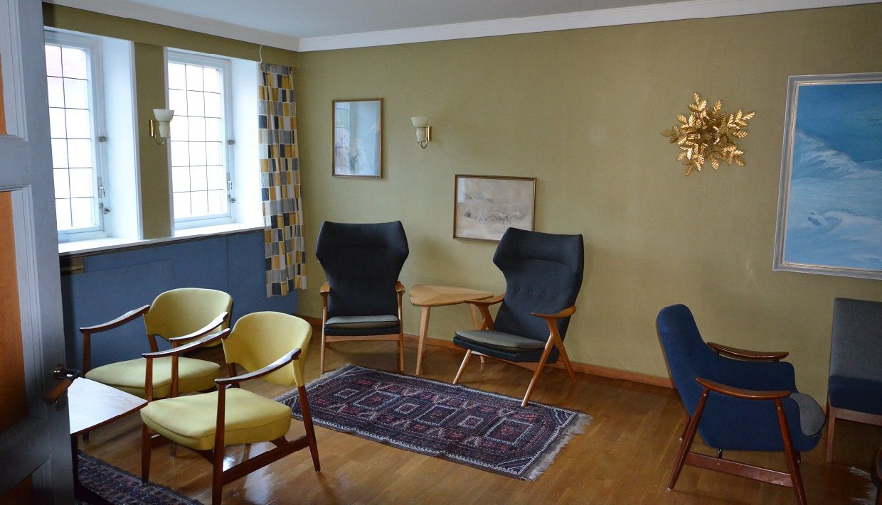 Noen bord og stoler i en sittegruppe, malerier på veggen over.