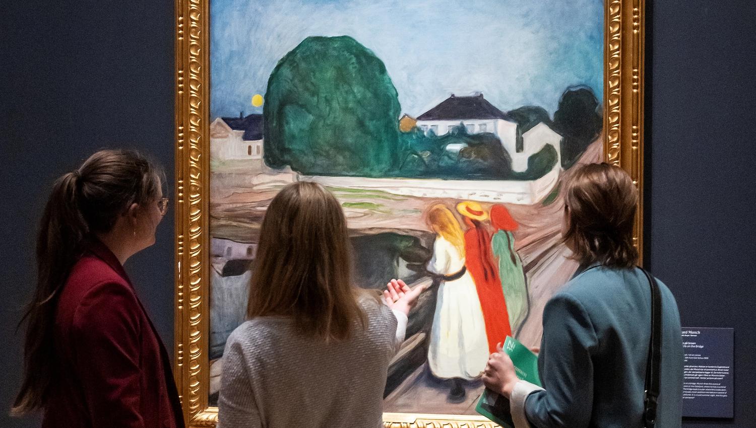 Tre jenter som ser på maleriet "Pikene på boren" av Edvard Munch.