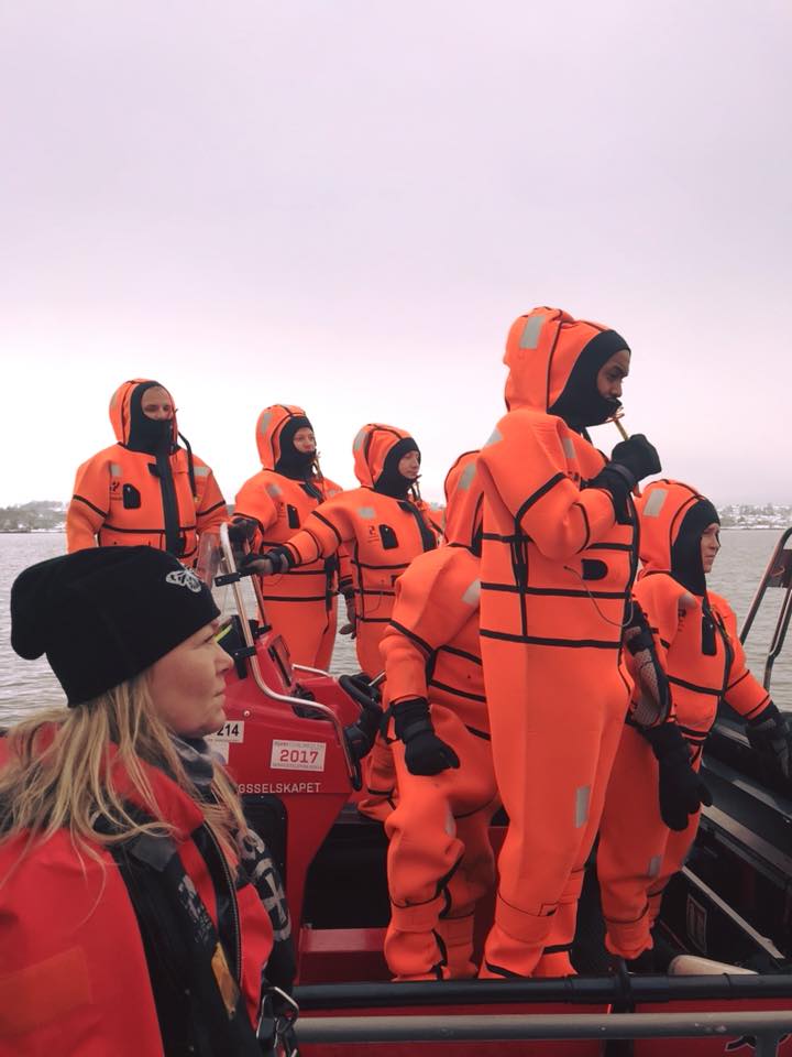 Mennesker i oransje drakter på båt